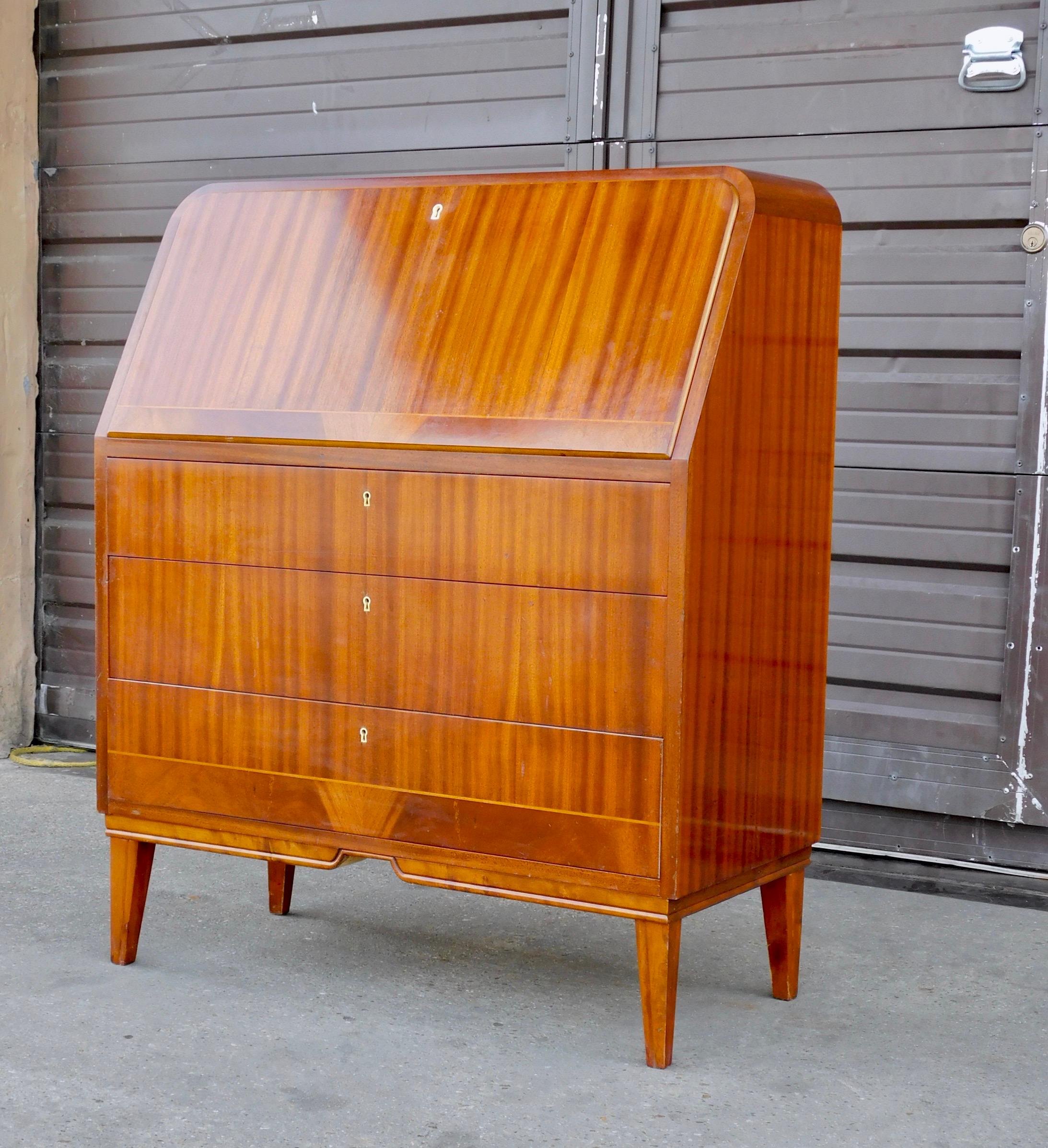 Swedish art moderne era secretaire desk rendered in striped mahogany. With interior in mahogany. Interior consists of slots and pullout / pull-out drawers. There is an area to conveniently store a lap top computer.
The three lower drawers function