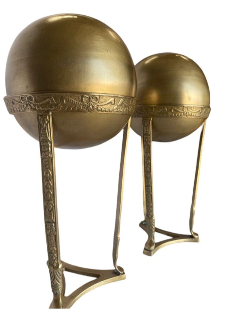 A pair of embossed brass crystal ball pedestals exude understated elegance. Crafted from gleaming brass, each pedestal features delicate embossing adding a touch of sophistication. Atop each pedestal sits a crystal ball, radiating clarity and