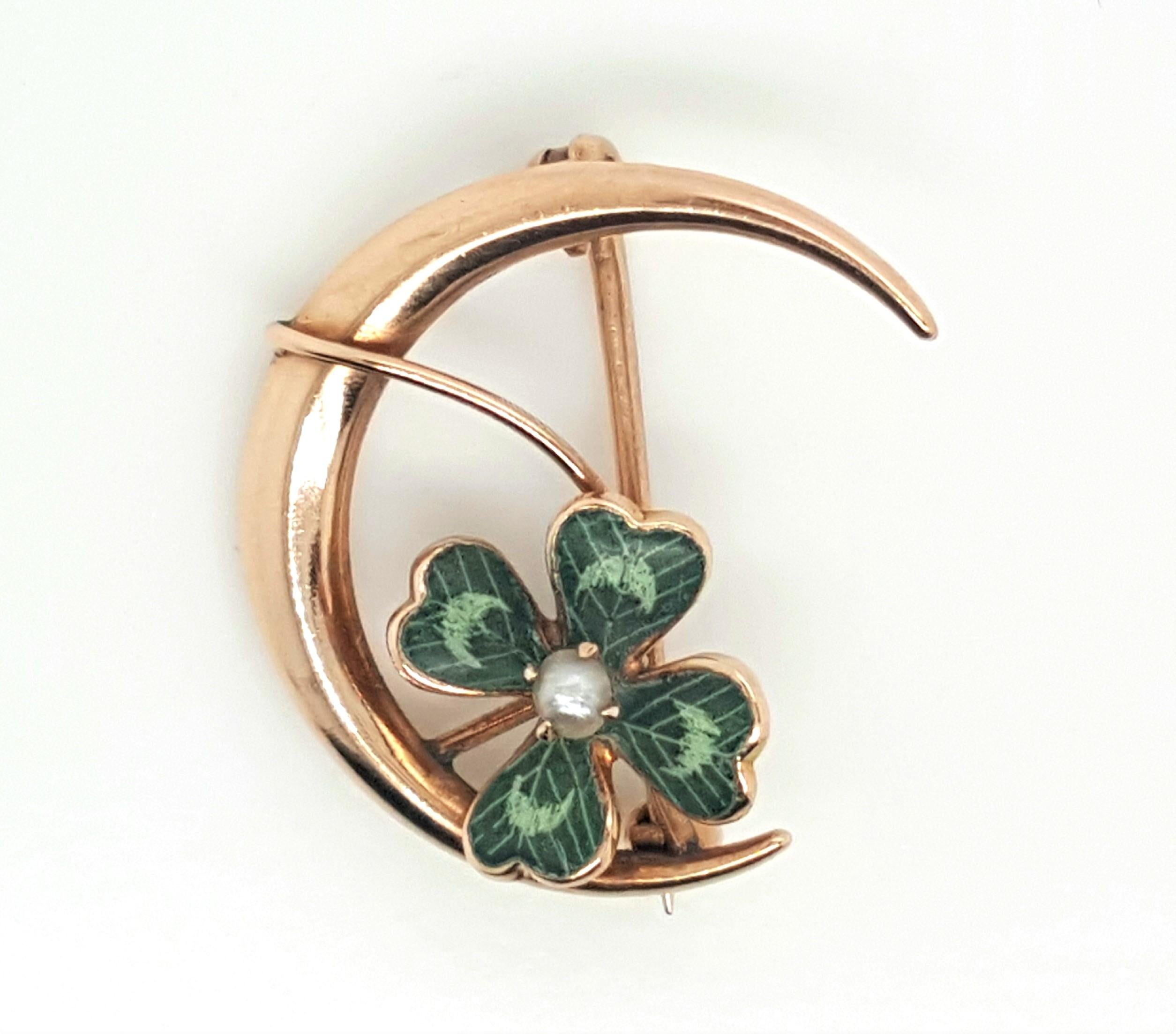 Art Nouveau 10 karat yellow gold brooch designed as a crescent moon featuring an enameled four leaf clover sweeping across the center, accented by half pearl.  A pinstem and C catch complete the reverse. The brooch weighs 1.32 grams.  Dimensions:
