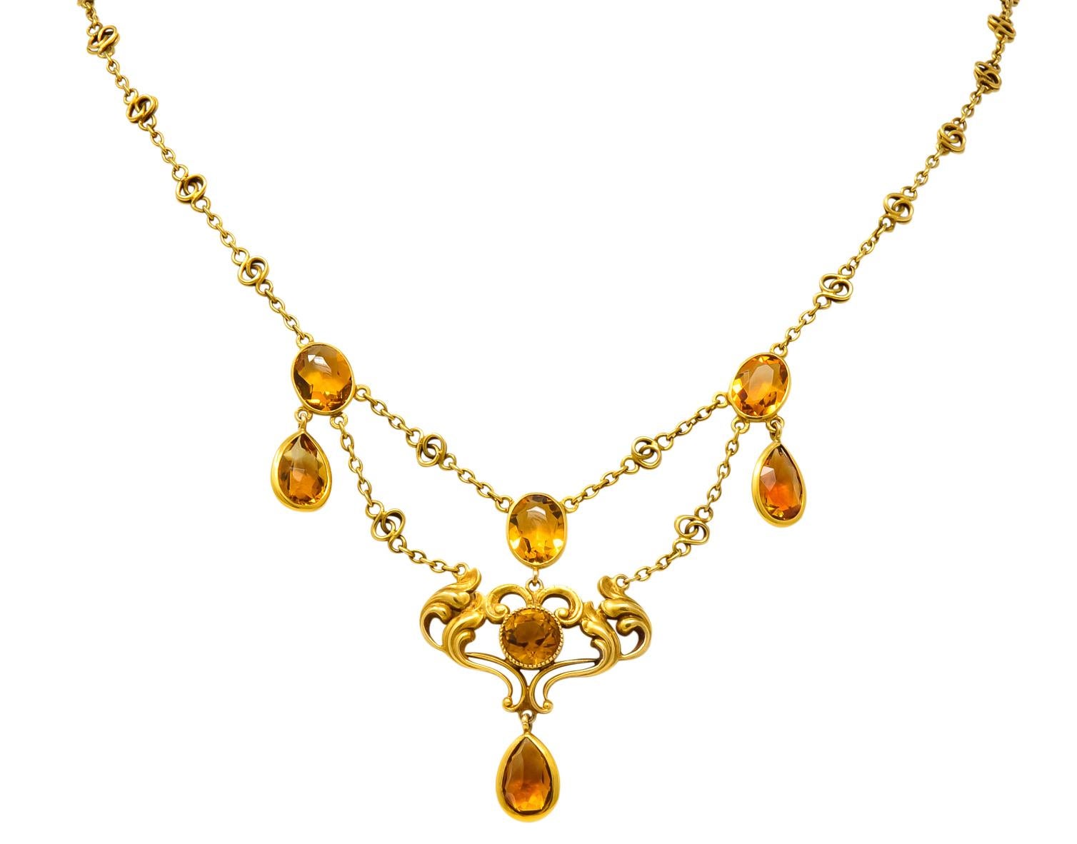Swag style with bezel set round, pear, and oval shaped citrines

Total citrine weight approximately 11.50 carats, deep rich orange and very well matched

With satin gold whiplash detail

On a decorative chain completed by spring ring clasp

Stamped