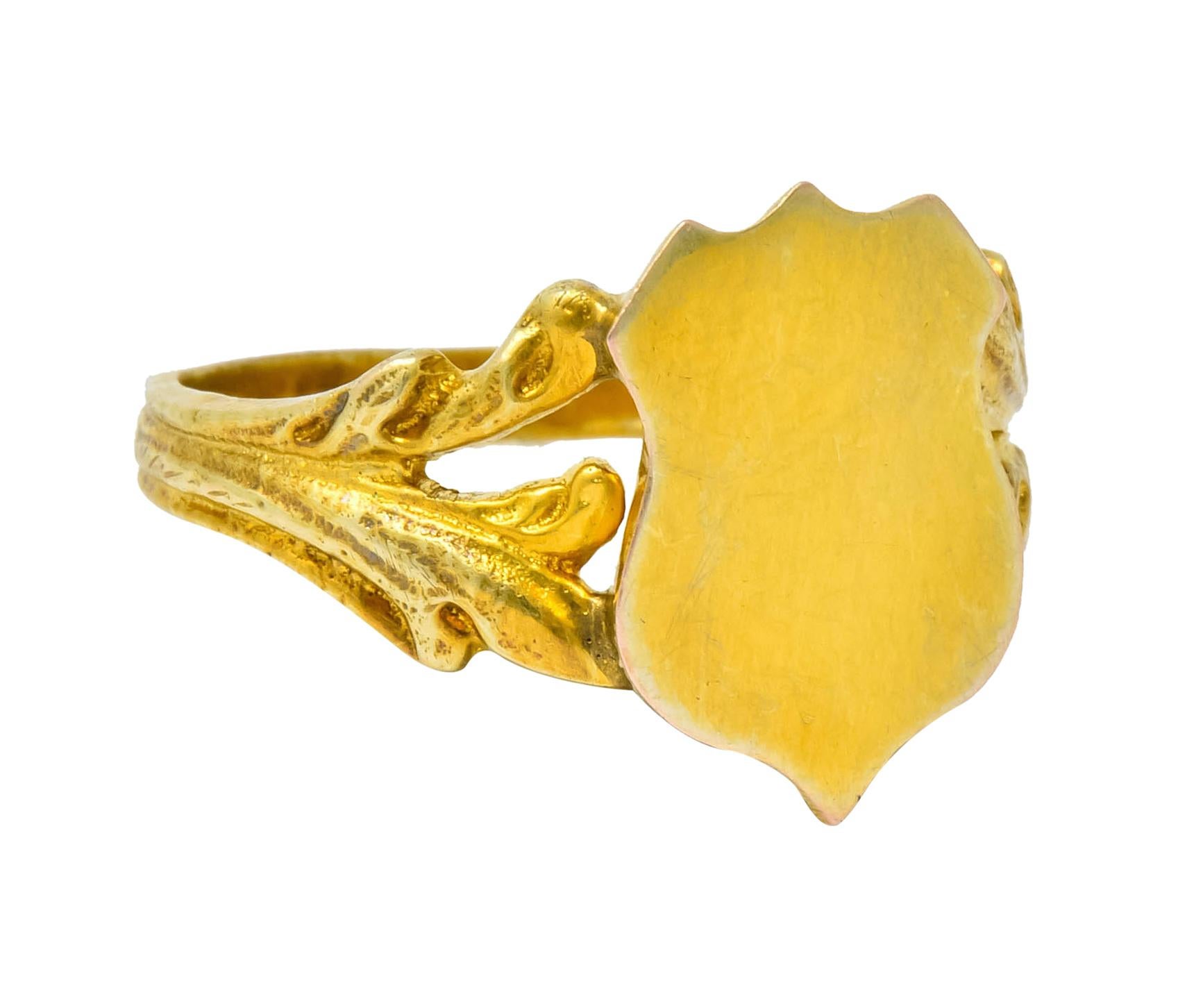 Signet style ring designed as a shield with a smooth, bright finish

Flanked by split shoulders with scrolling foliate motif and deeply ridged shank

Stamped K12 for 12 karat gold

Ring Size: 9 1/2 & sizable

Top measures: 15.8 mm and sits 2.4 mm
