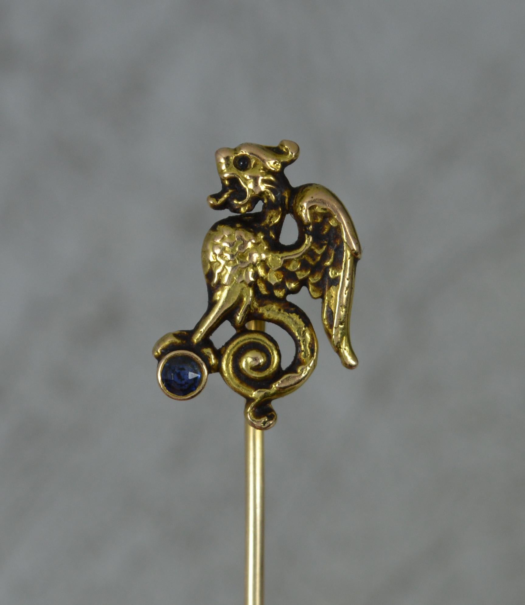 A superb art nouveau period stick tie pin. c1900-1905.
Straight pin with a griffin type creature to top holding a single round cut sapphire.
​63mm long, 11mm x 15mm head. 1.8 grams.
Solid 14 carat yellow gold example.

Condition ; Good for age.