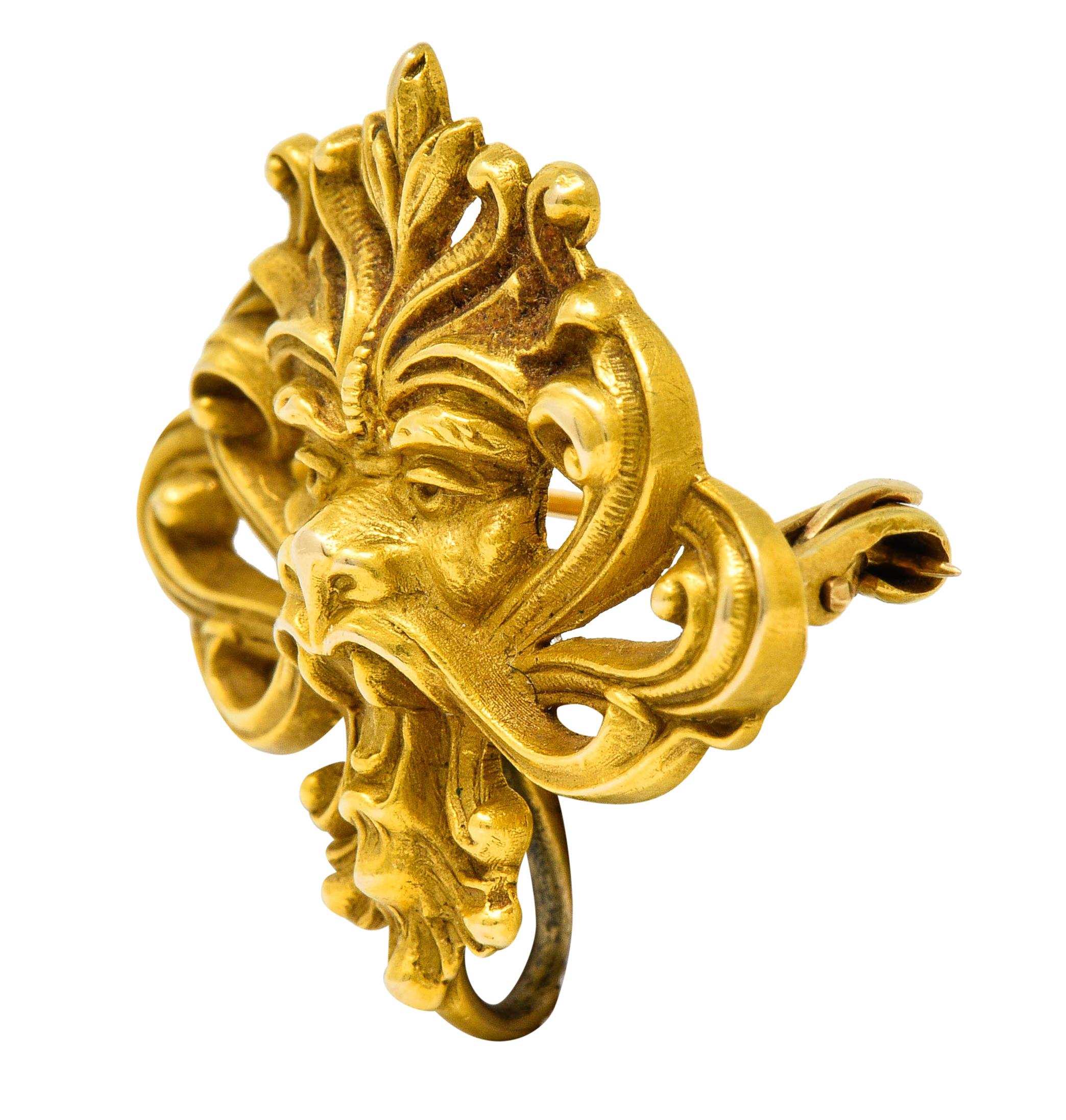 Brooch is designed as a Green man style roaring lion

With stylized whiplash and foliate as its mane

Completed by a pin stem with locking closure and a watch hook

Tested as 14 karat gold

Circa: 1905

Measures: 1 x 1 1/8 inches

Total weight: 3.9