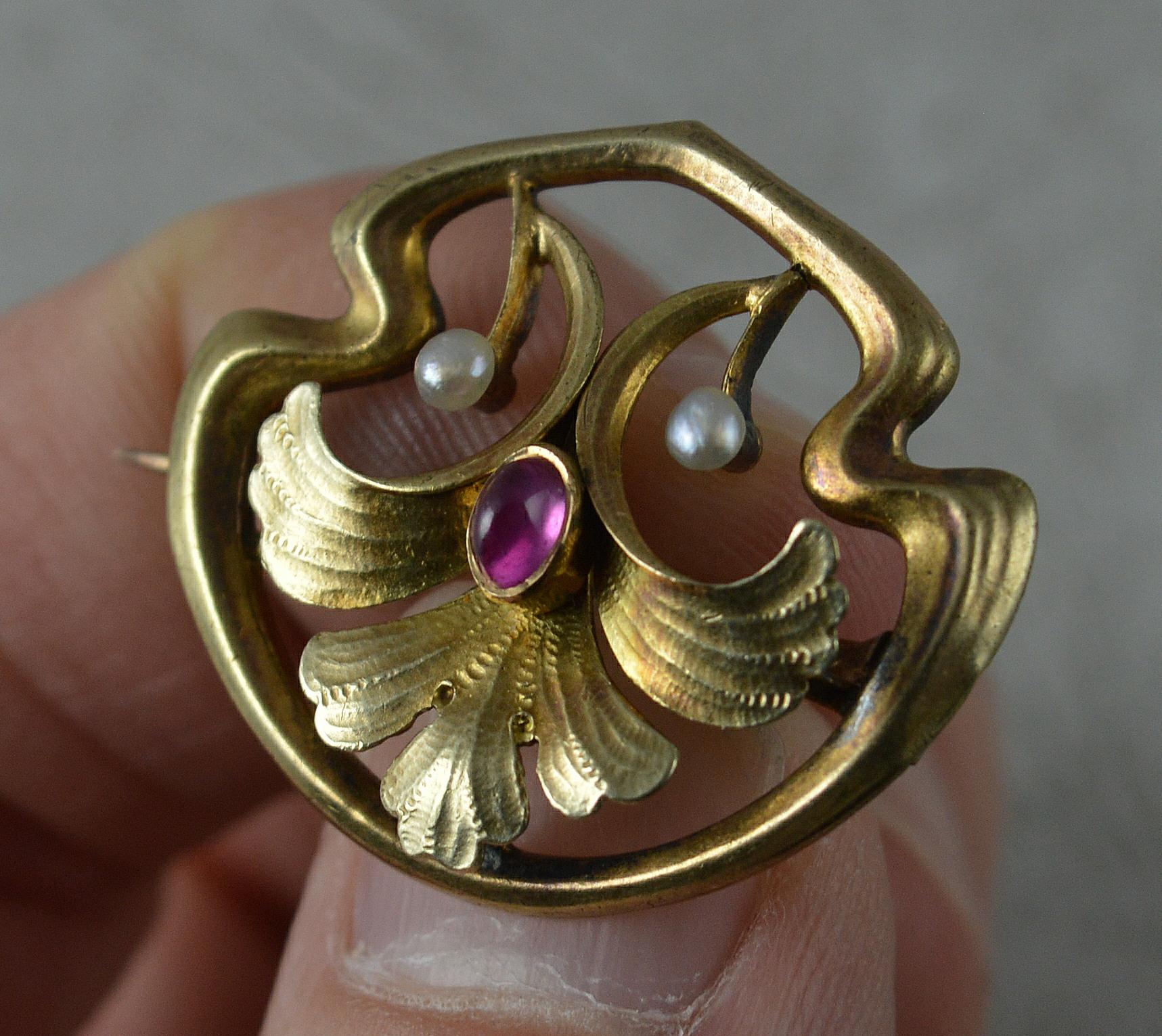 A stunning Edwardian era brooch.
Art nouveau shape and style, well made piece.
14 carat rose gold example. Designed with an oval ruby cabochon to centre and two smaller pearls. 
Stylish shape and floral details.

CONDITION ; Very good for age.