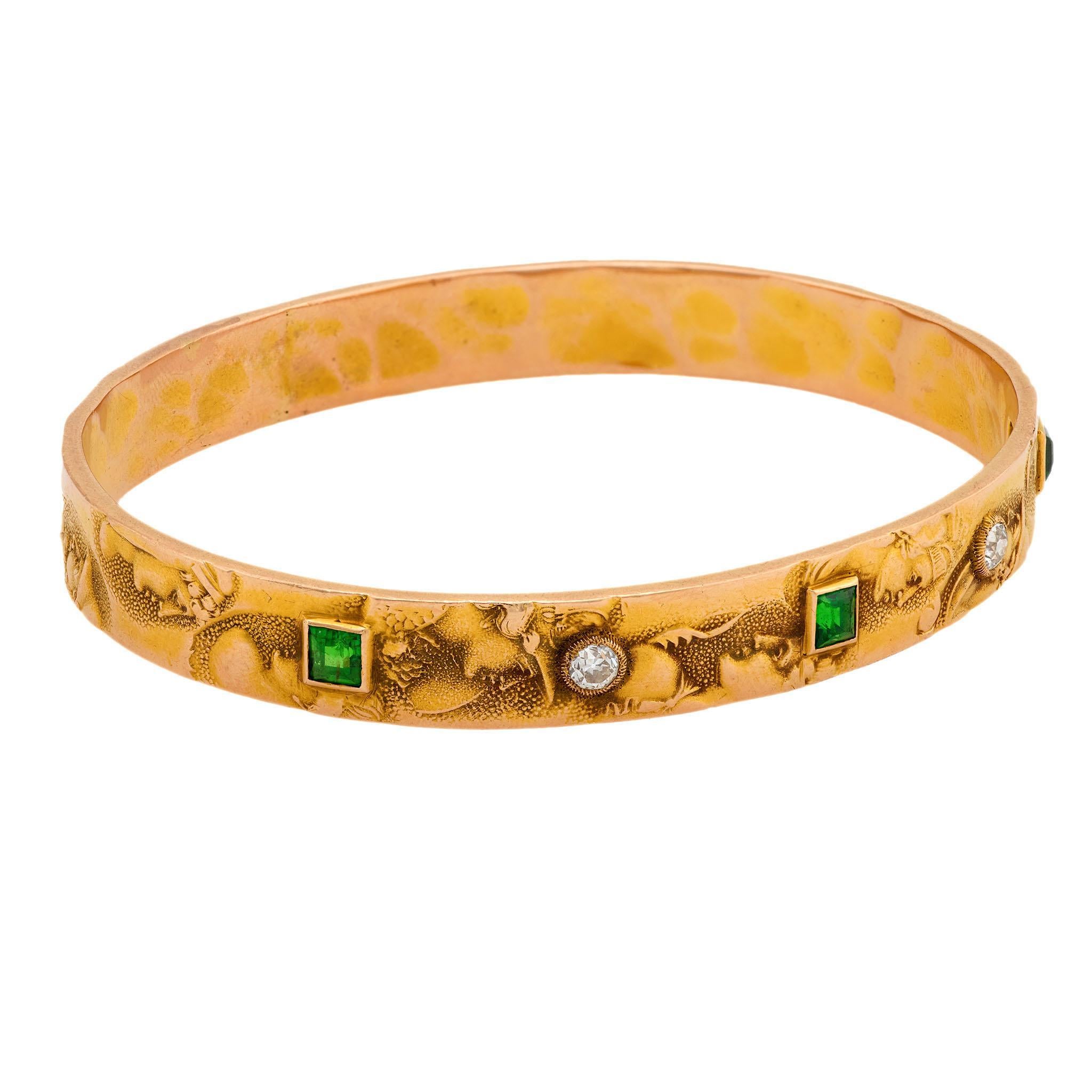 A gorgeous gemstone bangle bracelet from the Art Nouveau (ca1910s) era! Crafted in 14k vibrant yellow gold, this bangle features alternating diamonds and demantoid stones. The 2 diamonds, which are bezel-set are both old mine cuts, and have an