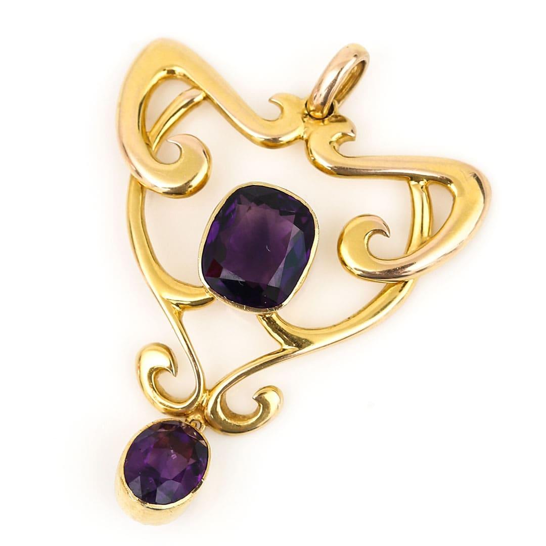 A quintessential Art Nouveau pendant set in 15ct gold with a central set amethyst and accompanying drop all masterfully crafted around 1910. The very pretty pendant with its highly cursive and sweeping styling made so popular during the Art Nouveau
