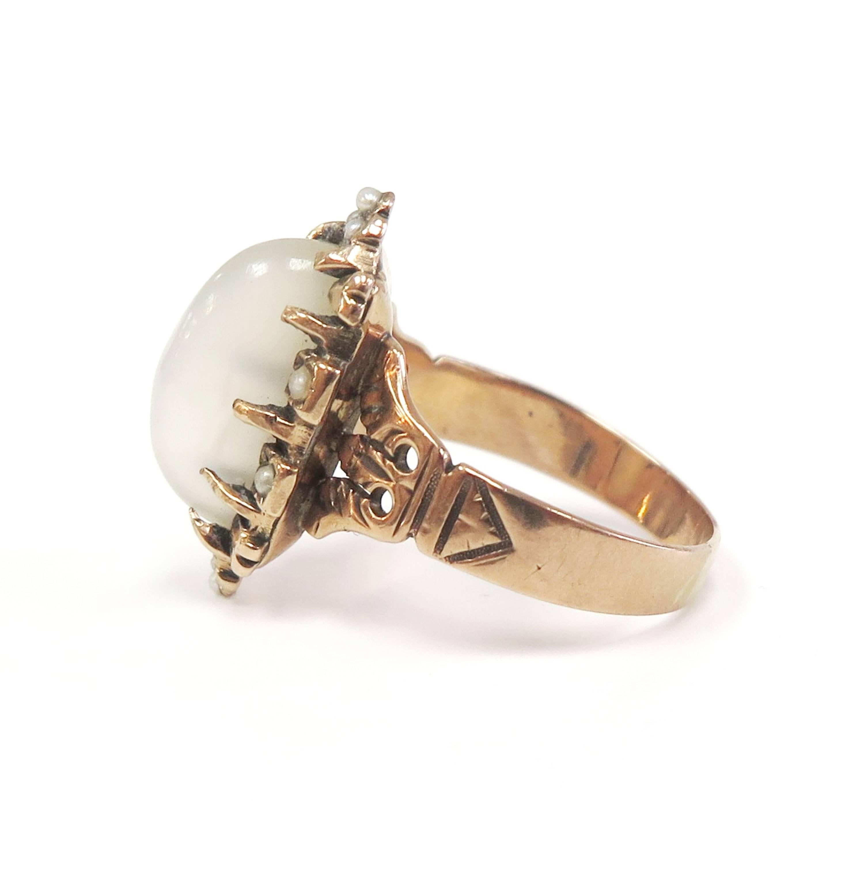 A gorgeous moonstone ring from the Art Nouveau (circa 1910) era! A beautiful oval-shaped moonstone cabochon rests at the center of the lovely 14 karat rose gold mounting. The moonstone is prong set and accented with delicate natural seed pearls. The