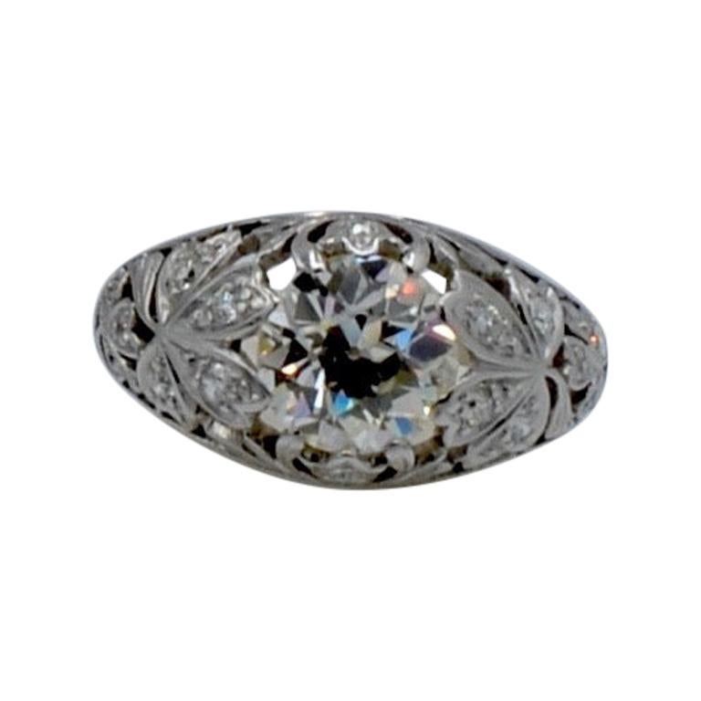 This beautiful ring is a real stunner!1 The center diamond is aprox. 1.65 ct old European mine cut diamond K color VS2 quality. The surrounding platinum floral design is accented with tiny diamonds throughout. The ring is a size 6 and can be sized.