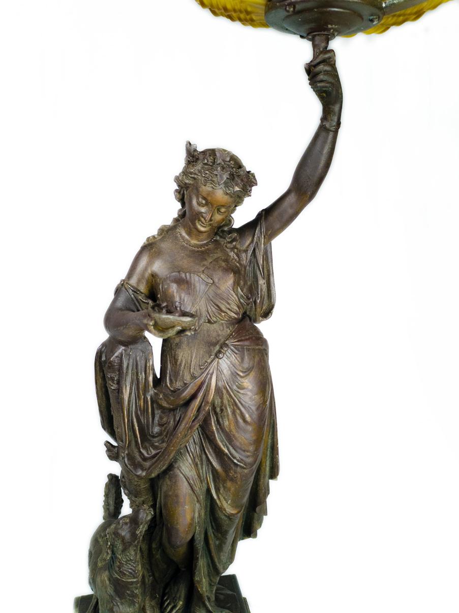 Grande statue Belle Epoque du 19ème siècle en terre cuite représentant une femme tenant un livre illuminé.  verre jaune en forme de tulipe.