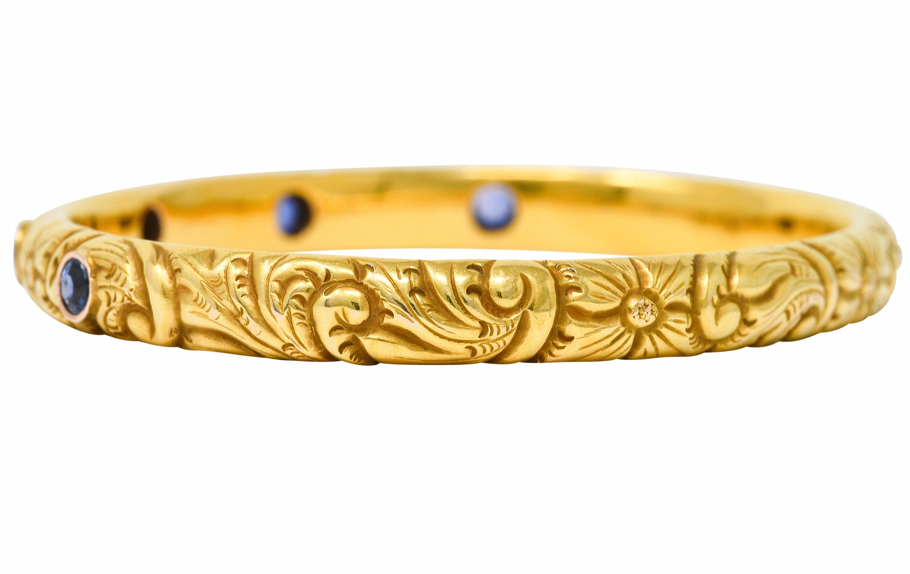 Mit fünf rund geschliffenen Saphiren mit einem Gesamtgewicht von etwa 2,10 Karat. Transparente mittel- bis hellblaue Farbe - Lünette auf der Vorderseite angebracht. Mit einem tief eingravierten, floralen Motiv. Gestempelt 14 für 14 Karat Gold.