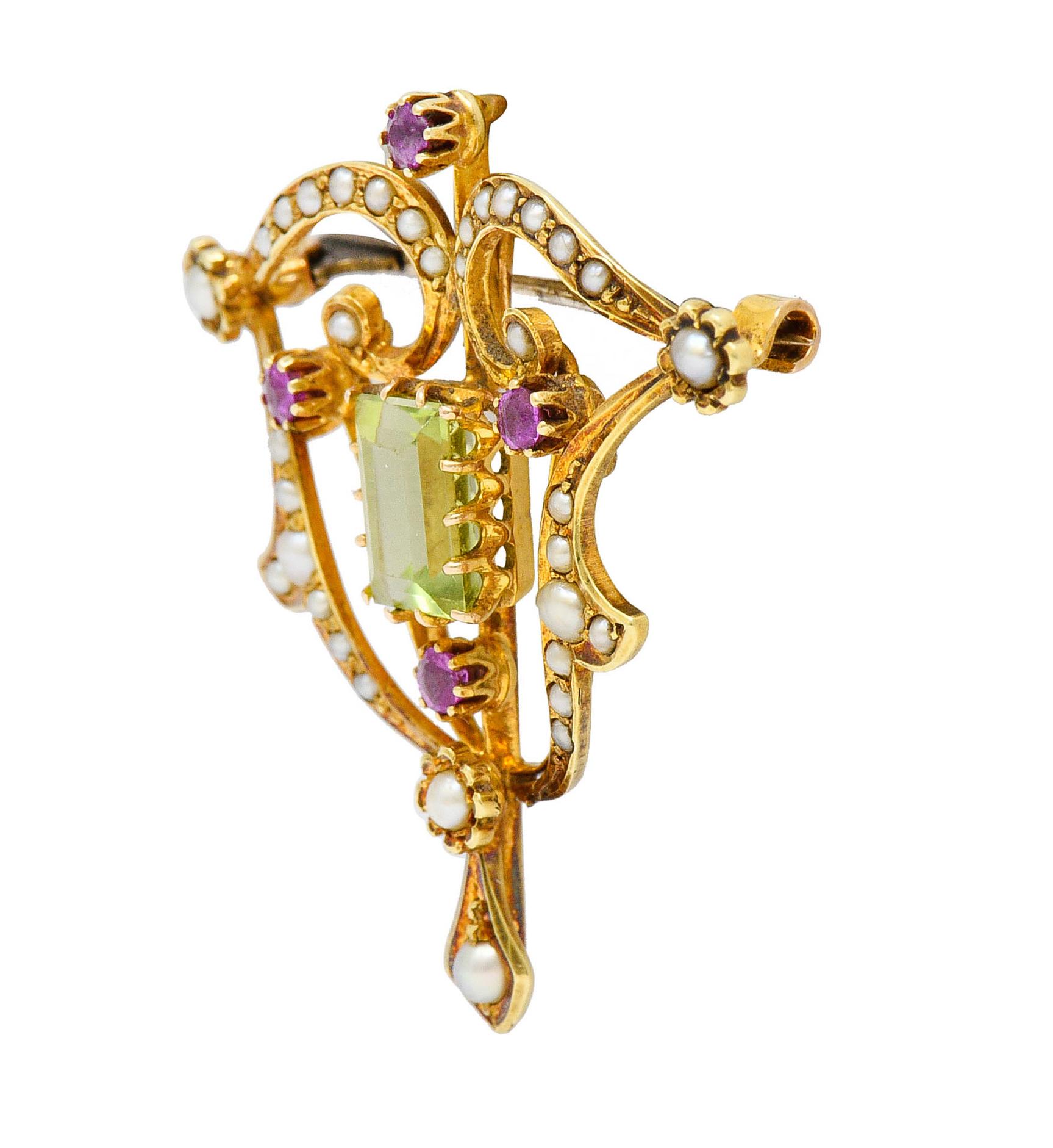 Pendant brooch is designed as scrolling whiplash and floral stations

Centering a rectangular step cut peridot weighing approximately 2.70 carats - bright yellowish green

With four round cut ruby accents weighing in total approximately 0.25 carat -