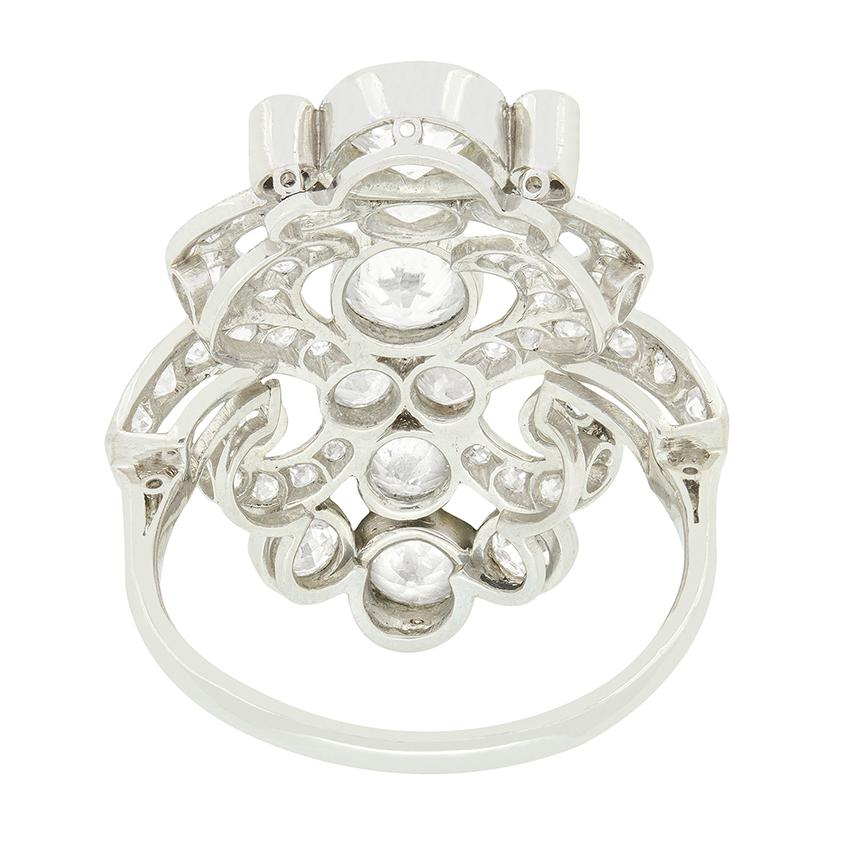 Este cautivador anillo de racimo francés del Art Nouveau exhibe un total de 3,05 quilates en diamantes talla antigua engastados en un ornamentado diseño de platino. El trío central presenta una piedra superior de 0,80 ct, una central de 0,50 ct y