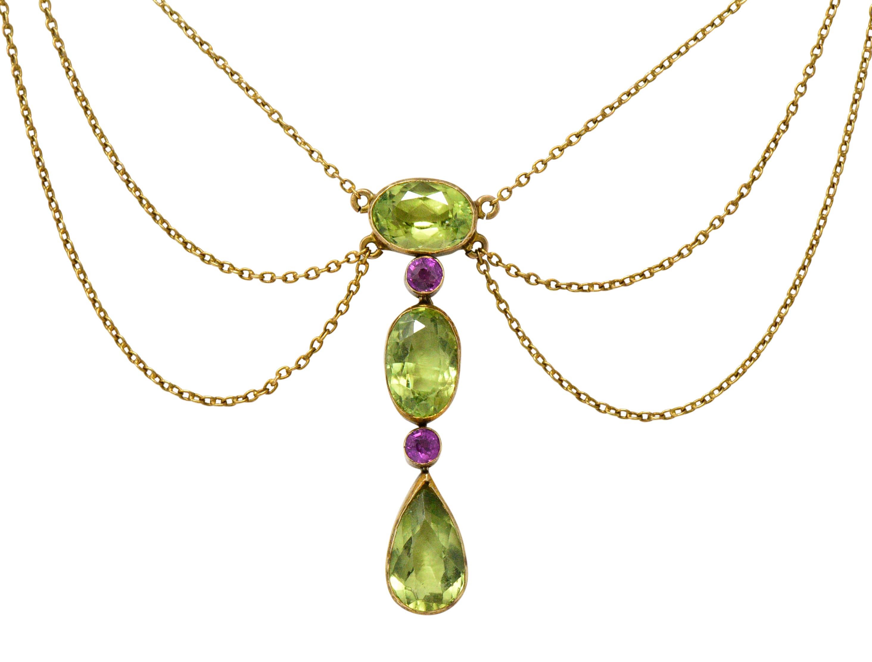 Swag style drop necklace centering six bezel set gemstones; symbolically suffragette in color

Larger stones are round, oval, and pear mixed cut peridot weighing approximately 6.45 carats; very well-matched and medium-light lime green in
