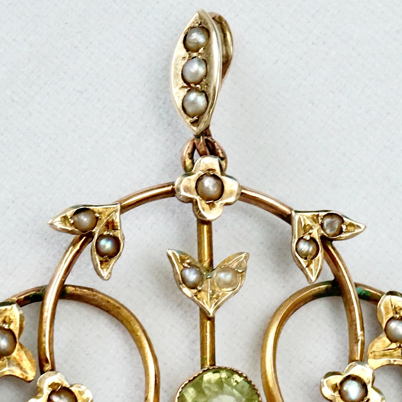 Art Nouveau 9ct gold lavaliere pendant with leaf and flower decoration, and featuring two lovely peridot paste stones and natural seed pearls. The peridots are bezel set with millgrain surround decoration. The pendant is a combination of yellow and