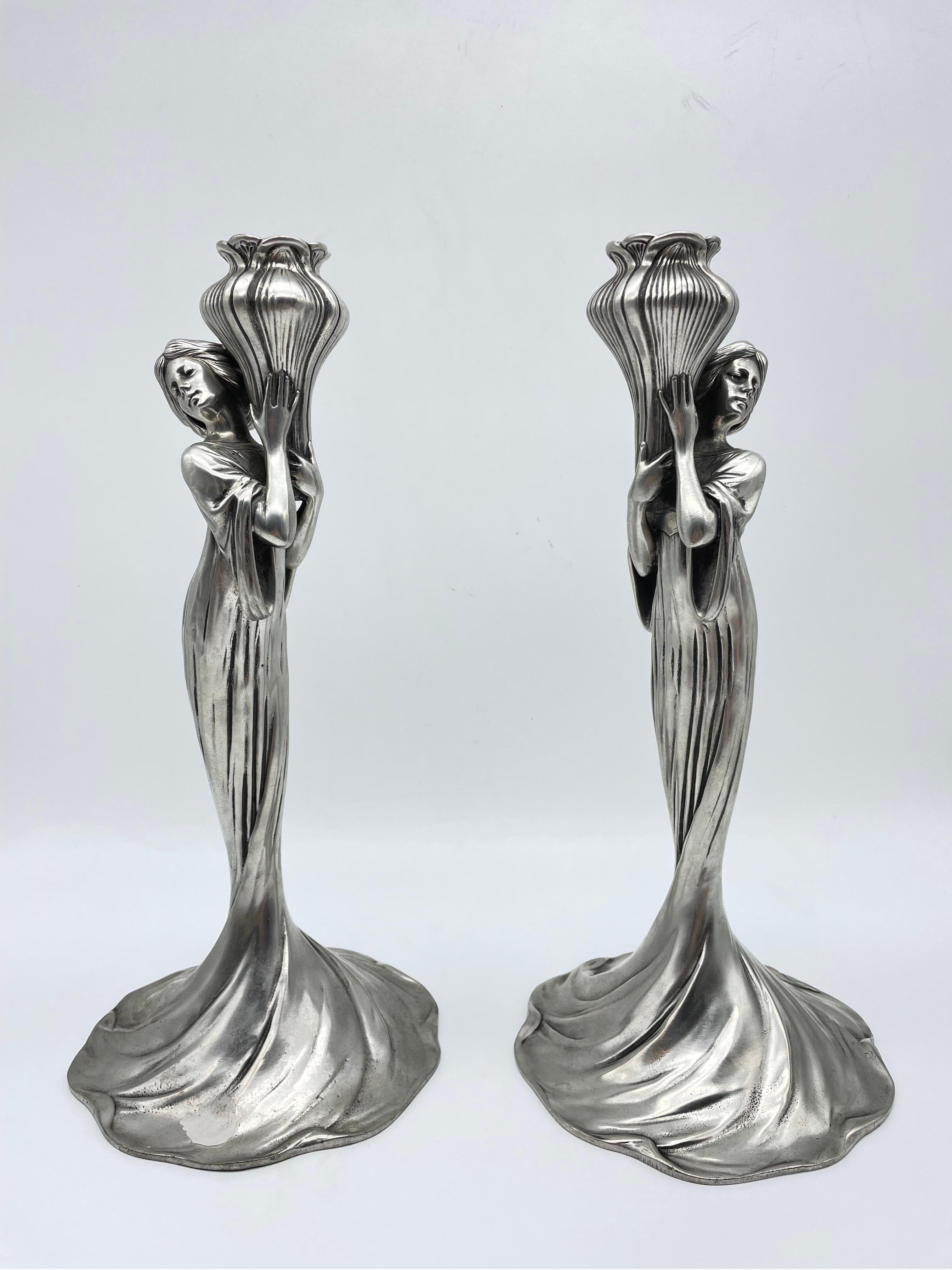 Paire de bougeoirs en étain allemand Art Nouveau d'Achille Gamba (italien, 1881 - 1941) pour Edles Zinn (Pewter), avec un motif figuratif représentant des femmes tenant des pistils de fleurs. Chaque pièce est entièrement poinçonnée sur le fond.