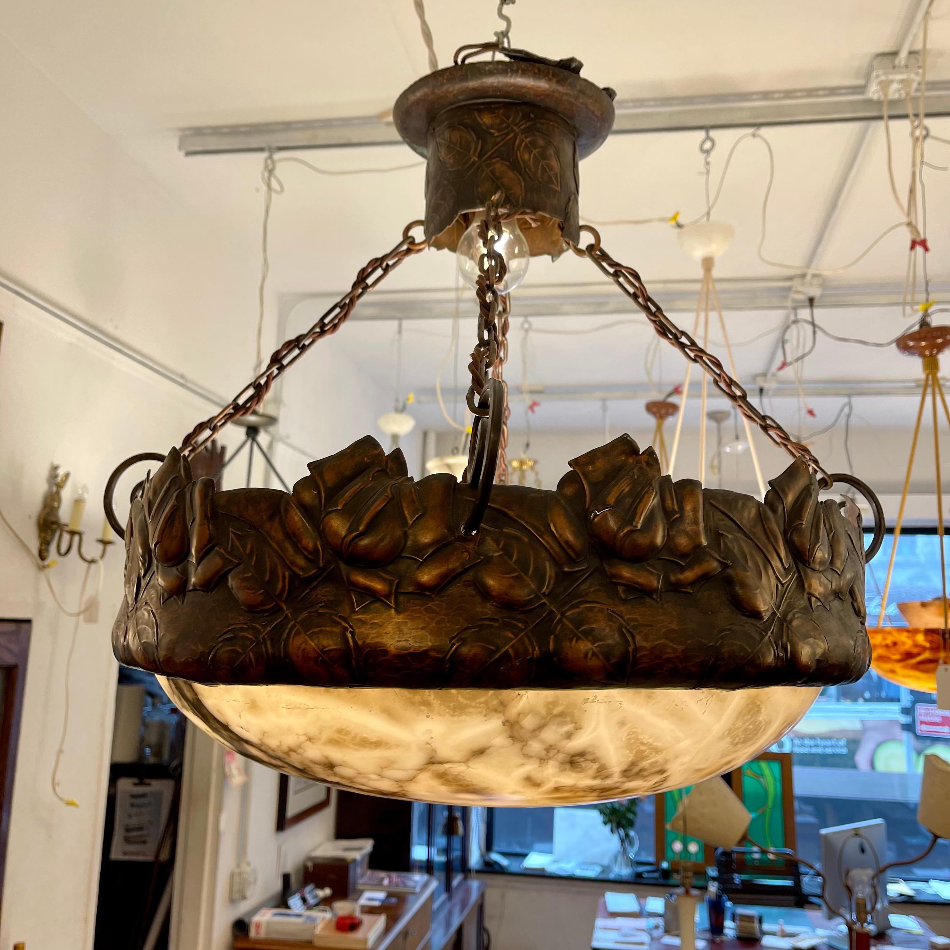 A highly figured alabaster stone shade is suspended in a gorgeous hammered copper collar. Repoussaged young roses adorn the top of the collar, with custom chain and electrified canopy to match. Mounts four standard bulbs in the shade with max