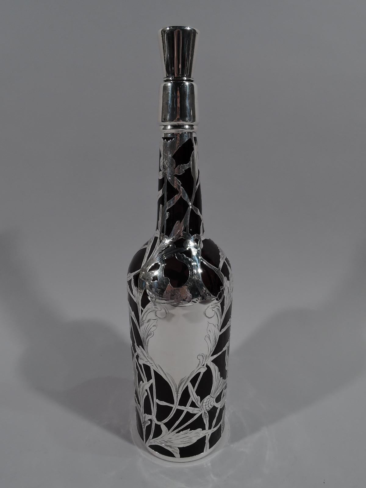 Turn-of-the-century Art Nouveau amber glass bottle decanter with engraved silver overlay. Made by La Pierre in New York. Traditional cylindrical form with sloping shoulder and upward tapering neck. Open and interlaced silver overlay with thistle