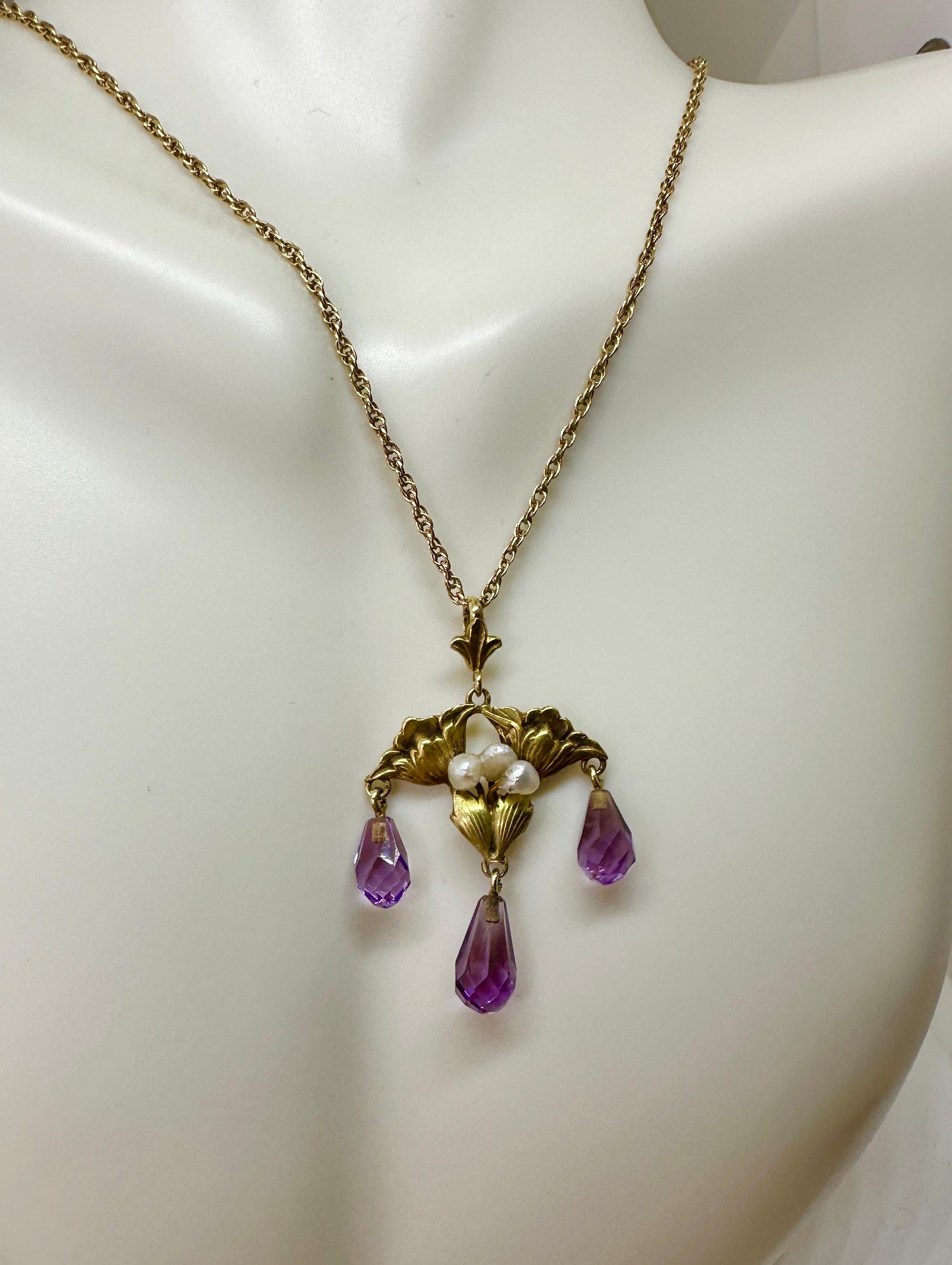 THIS IS A STUNNING ANTIQUE AMETHYST ART NOUVEAU FLOWER MOTIF PENDANT IN 14 KARAT GREEN GOLD WITH THREE BRIOLETTE CUT AMETHYST DROPS.
The exquisite necklace has three briolette faceted natural amethyst drops hanging from a lotus or poppy flower motif