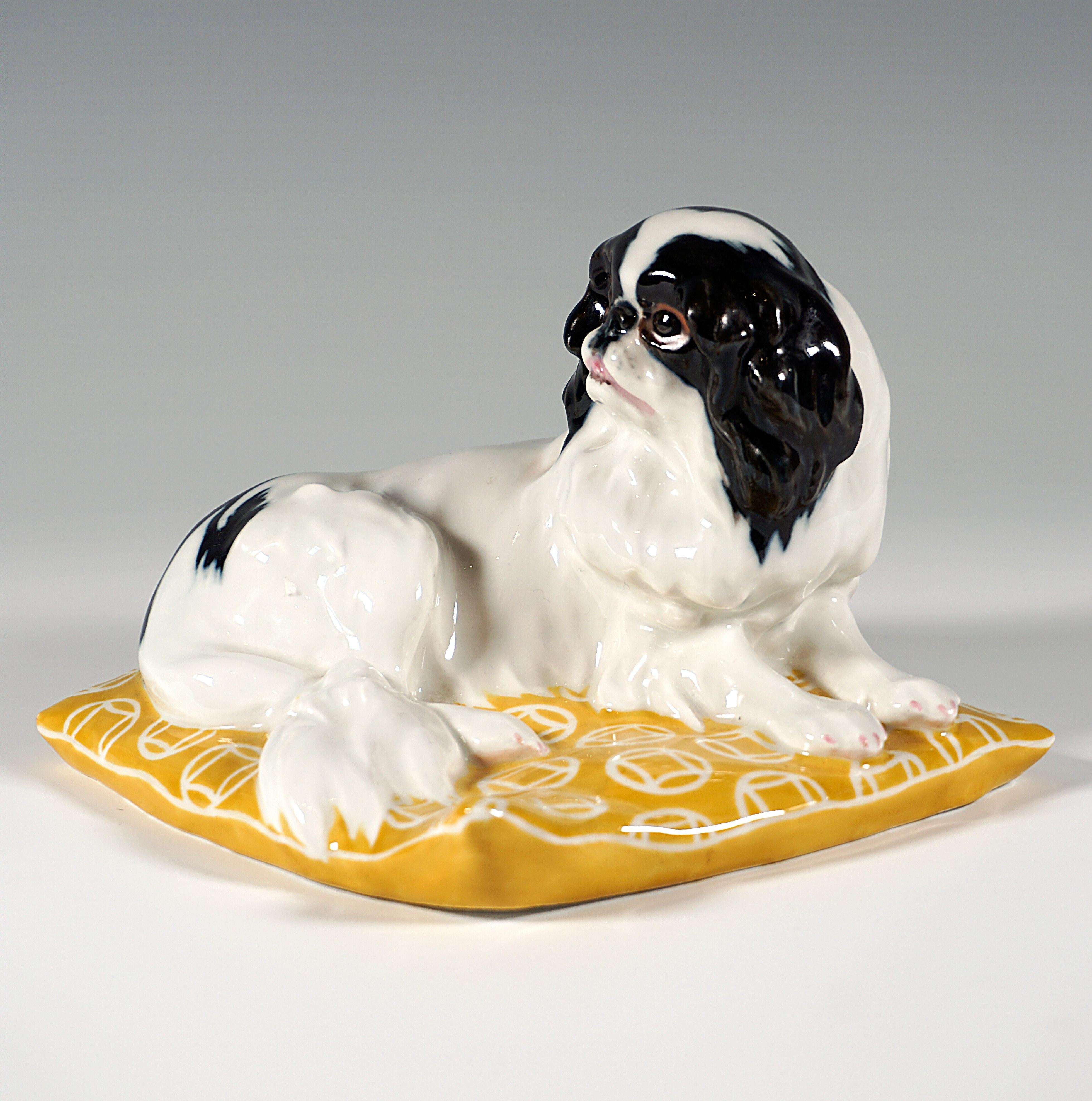 Rare Meissen Art Nouveau porcelain figurine:
Very lively representation of a Japan Chin dog with white and black fur on a large yellow pillow with a circular Art Nouveau decor.

Designer:
OSKAR ERICH HOESEL (1869 - 1951) was a German sculptor