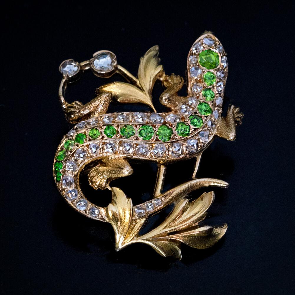 Circa 1890s  The 14K gold brooch is designed in Art Nouveau taste as a lizard crawling on a branch. The brooch is embellished with well matched Russian demantoids of a vivid green color and sparkling old rose cut diamonds.  Width is 26 mm (1 in.)