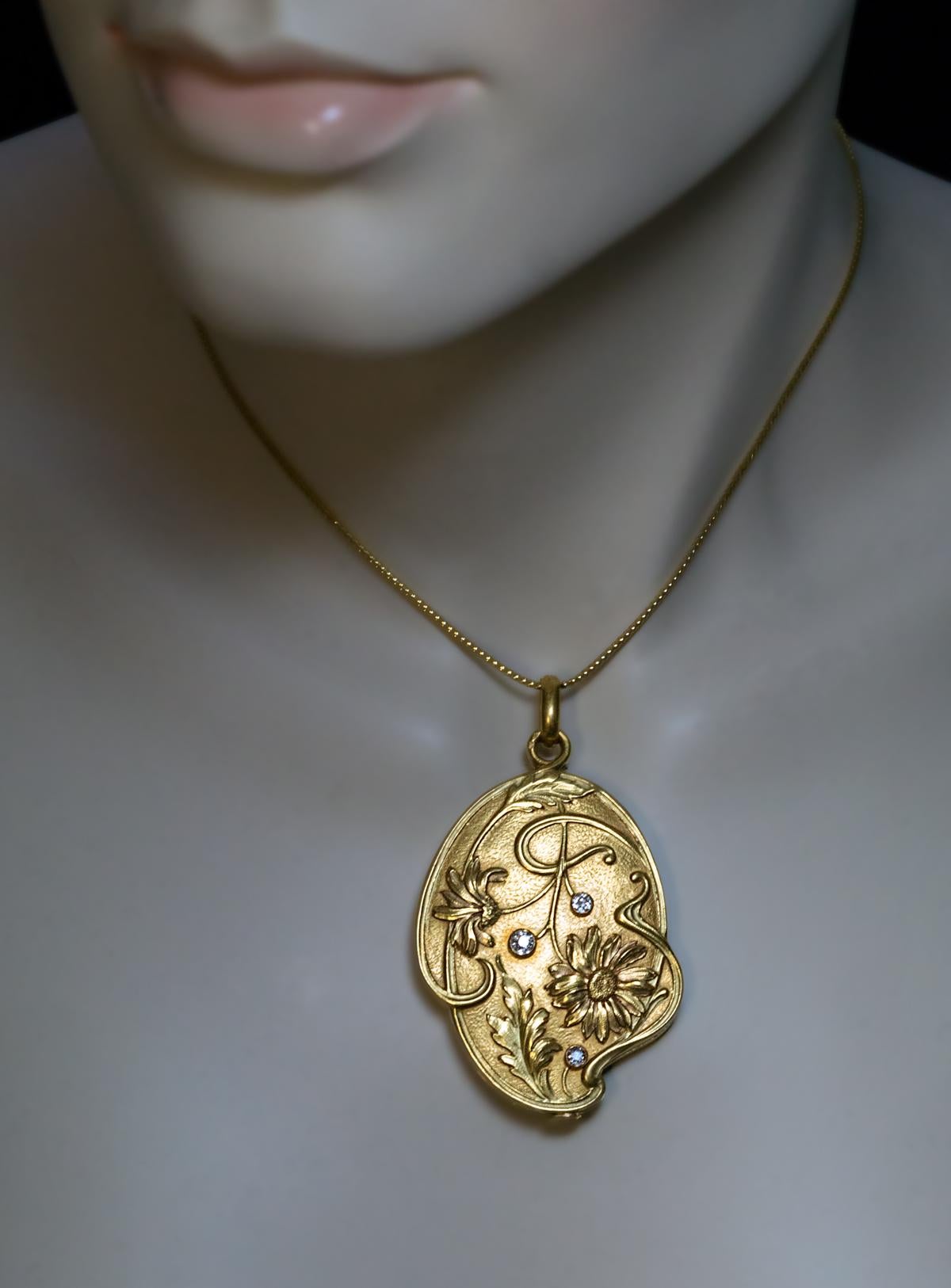 This large antique French 18K gold locket pendant is superbly modeled in the Art Nouveau style of the 1890s – early 1900s. The cover is finely chased in high relief with flowers accented with three sparkling old mine cut diamonds. The interior is