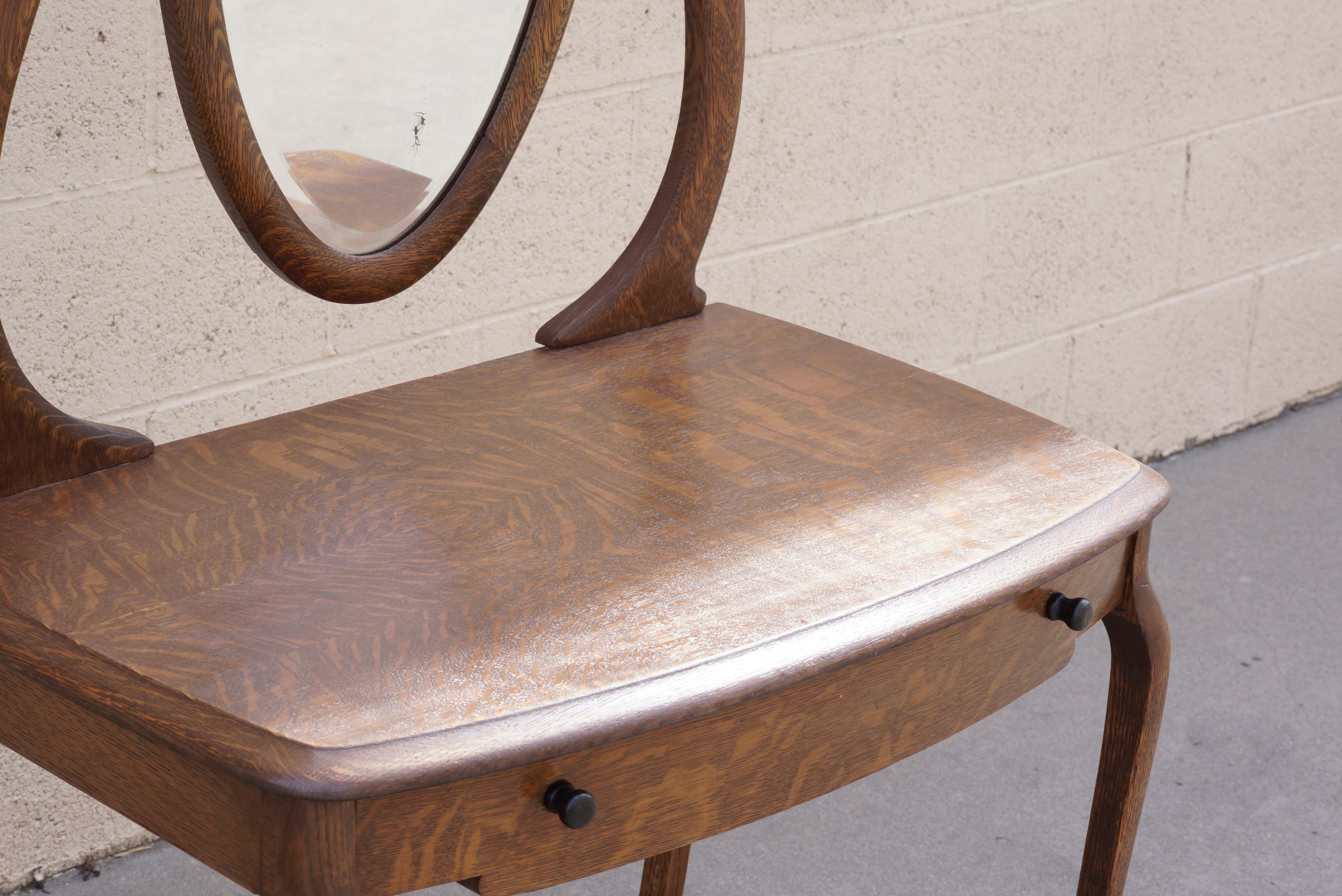 Lovely turn of the century antique vanity of tiger oak with hinged (adjustable) glass mirror and single drawer. Original mirror and painted wood drawer pulls. Wonderful organic curves and rich wood grain pattern. Reconditioned wood. In very good