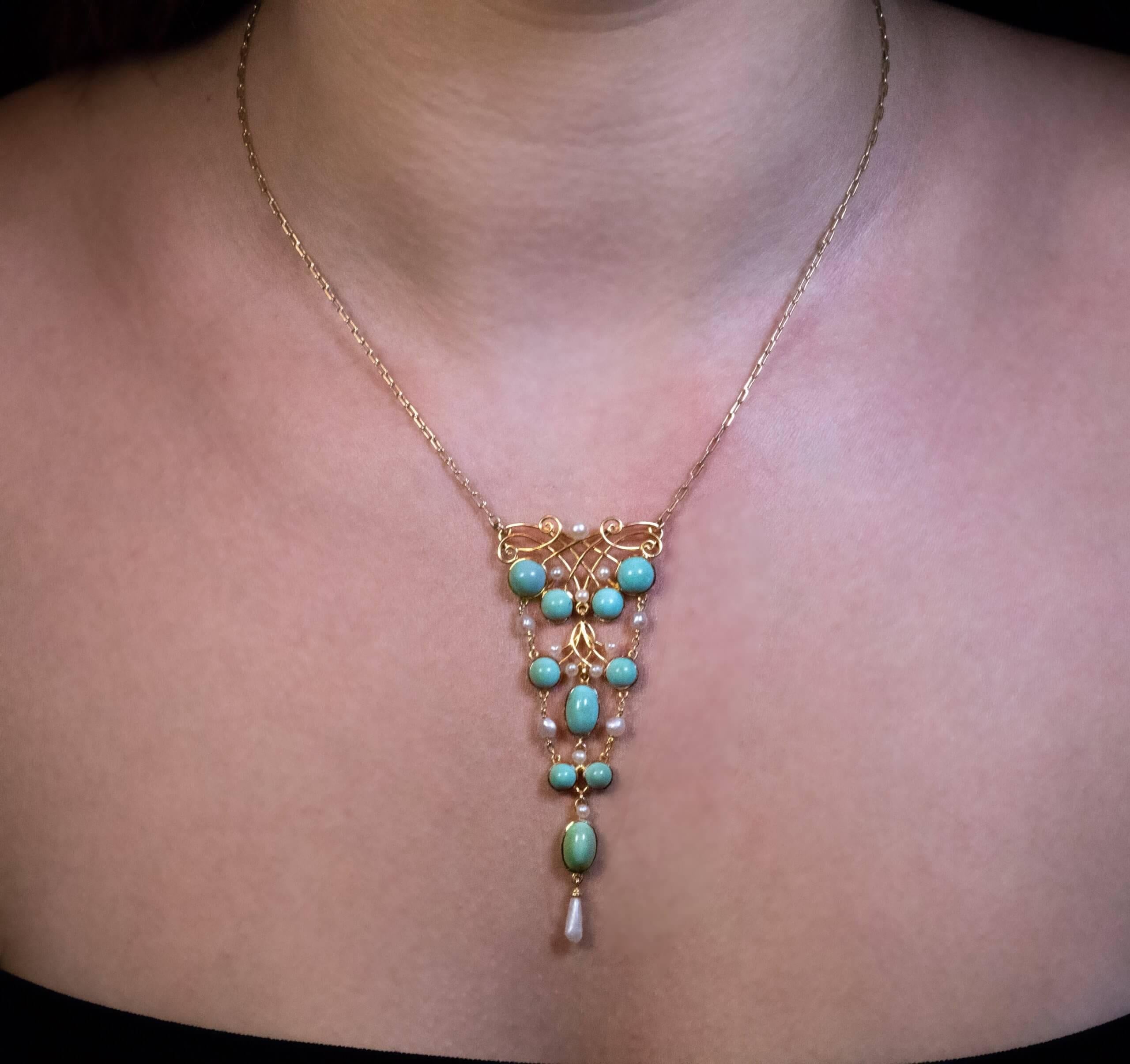 Circa 1910  This Art Nouveau era 14K yellow gold necklace is embellished with turquoise cabochons accented by pearls.  Total length of the pendant is 80 mm (3 1/8 in.)  Width is 32 mm (1 1/4 in.)  Length of the chain is 40 cm (16 2/8 in.)