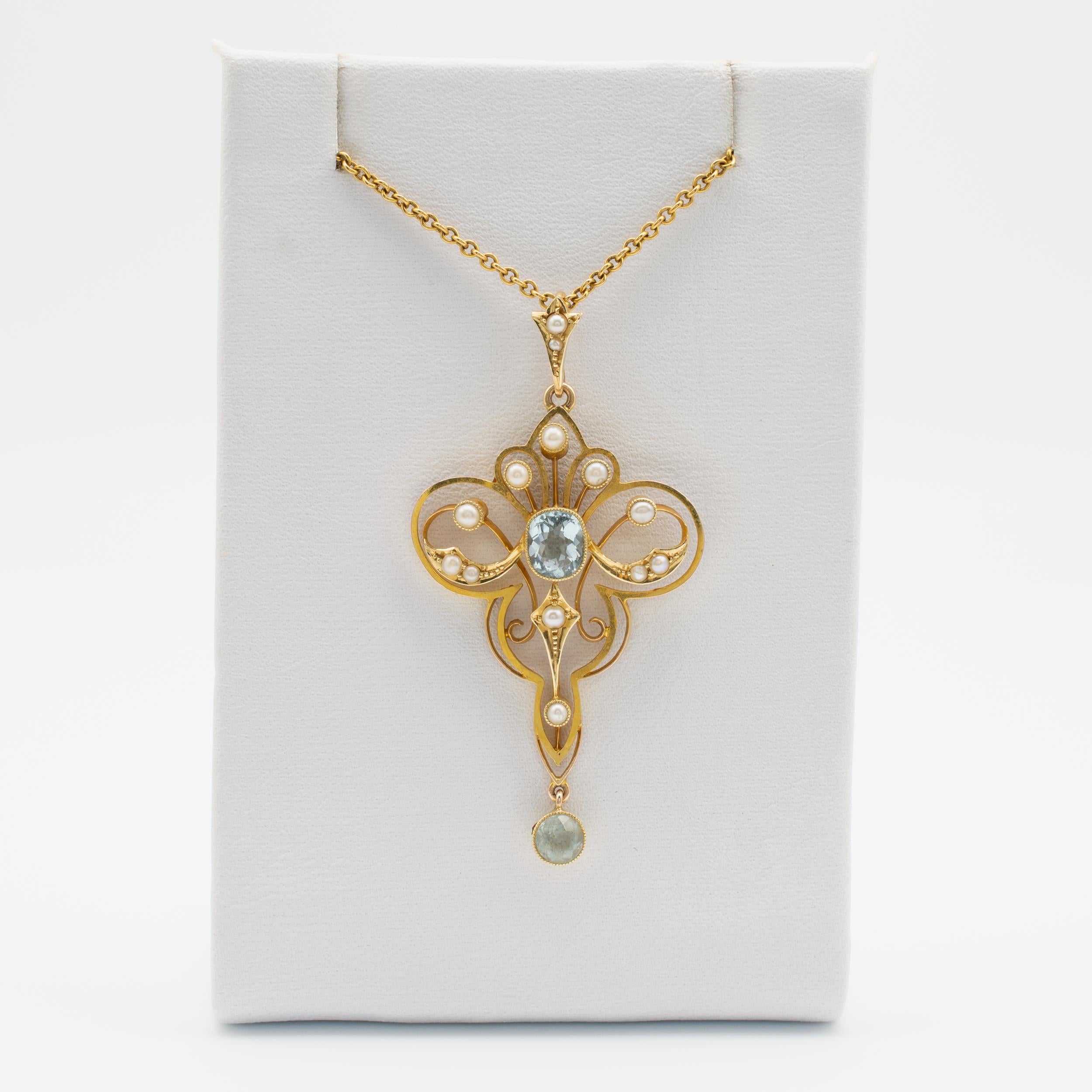 This exquisite Art Nouveau lavaliere pendant with aquamarines and seed pearls is crafted in 15 karat yellow gold and comes complete with 15-inch gold chain.

The delicate 15k gold trefoil shaped frame with scrolls is set to the center with a 0.70ct