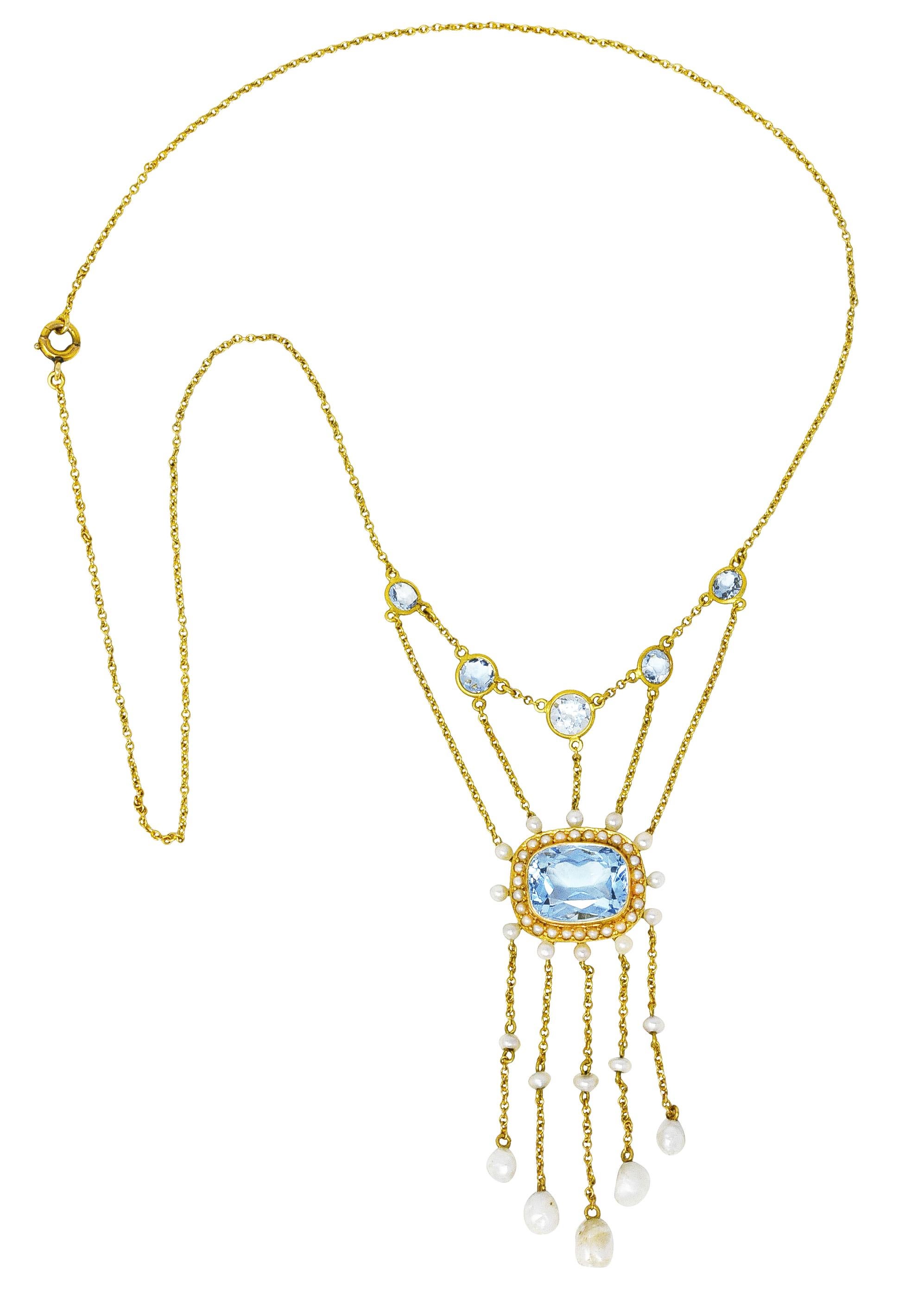 Necklace features a swagged central station featuring rectangular cushion and round cut aquamarines. Bezel set and weighing approximately 7.15 carats total. Transparent blue in color with light saturation - eye clean. With round pearl halo surround