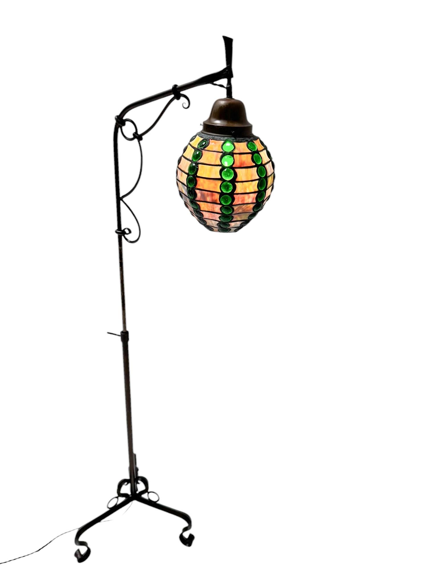 Splendida ed elegante lampada da terra in stile Art Nouveau Arts & Crafts, dal design francese del 1900. Struttura originale in ferro battuto patinato con paralume in vetro multicolore.Questa meravigliosa lampada da terra Art Nouveau Arts & Crafts è