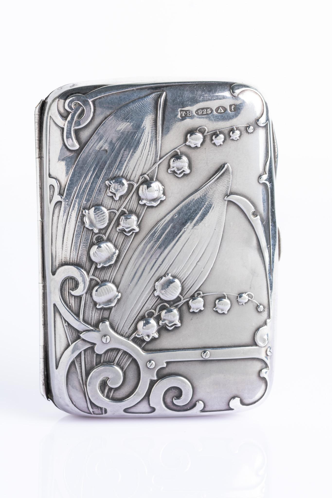 Un étui à cigarettes en argent sterling de style Art nouveau, richement décoré en haut relief d'un motif de muguet parmi des courbes sinueuses en forme de coup de fouet. Le design est caractéristique de l'orfèvre parisien Charles Murat, réputé pour