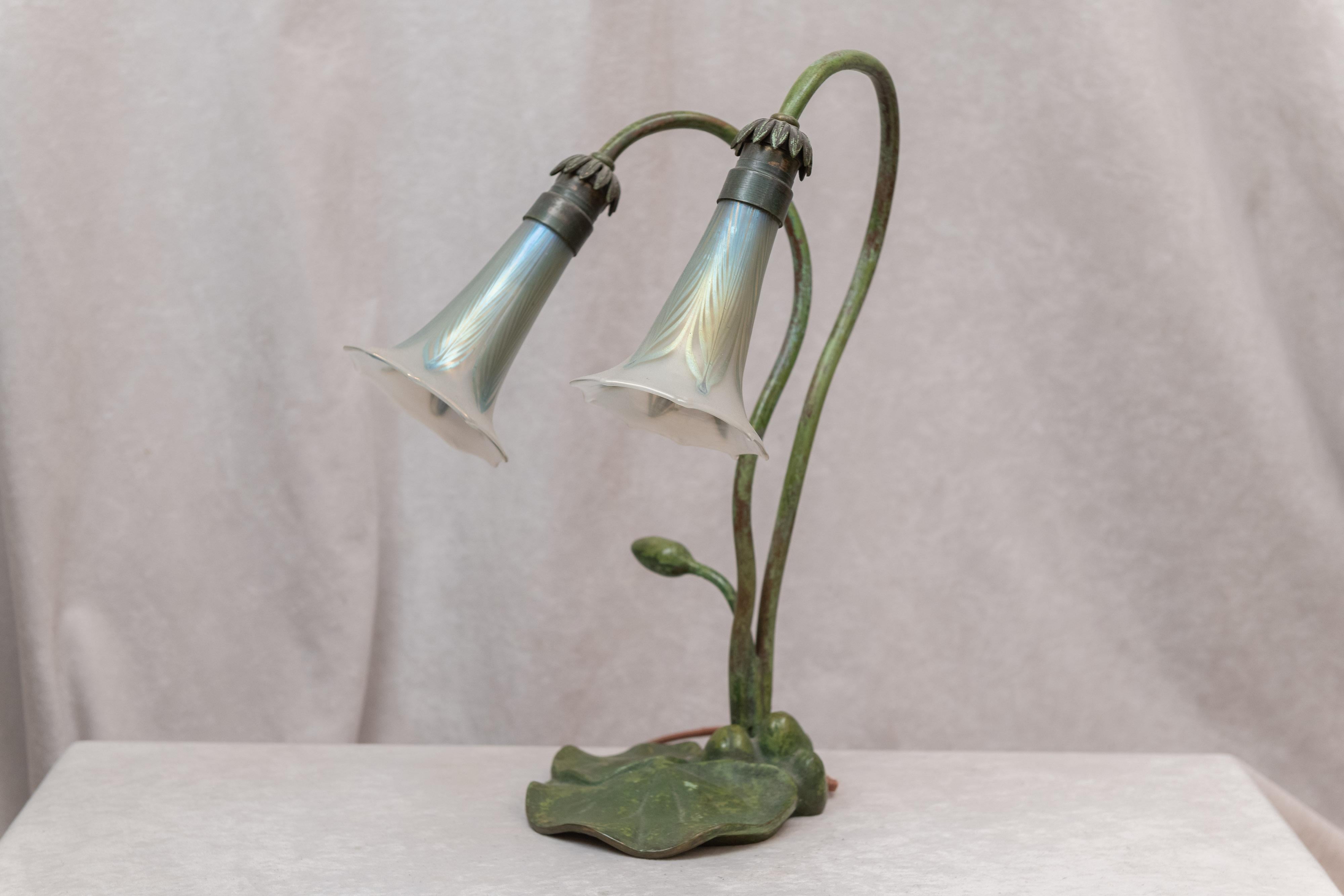 This little lamp is a wonderful addition for the art nouveau lover, or anyone else who appreciates fine work and beautiful lines. The bronze base still retains it's original green patina and the 2 glass shades are done in the pulled feather design.