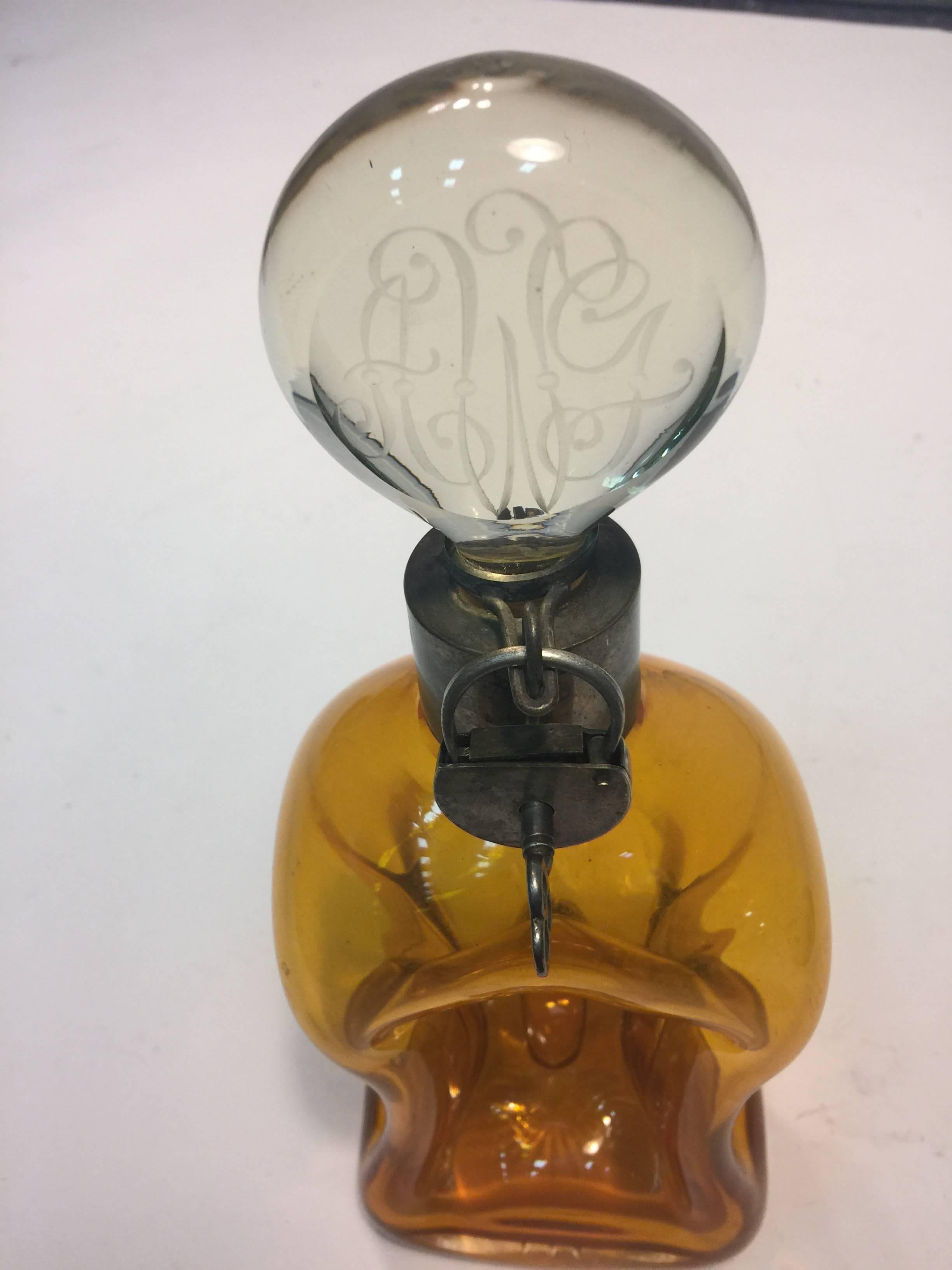 Art Nouveau amber glass decanter, circa 1900 with handmade silver metal lock and key and collar. Marked Austria on collar. The skeleton key unlocks and locks to access the clear glass stopper.