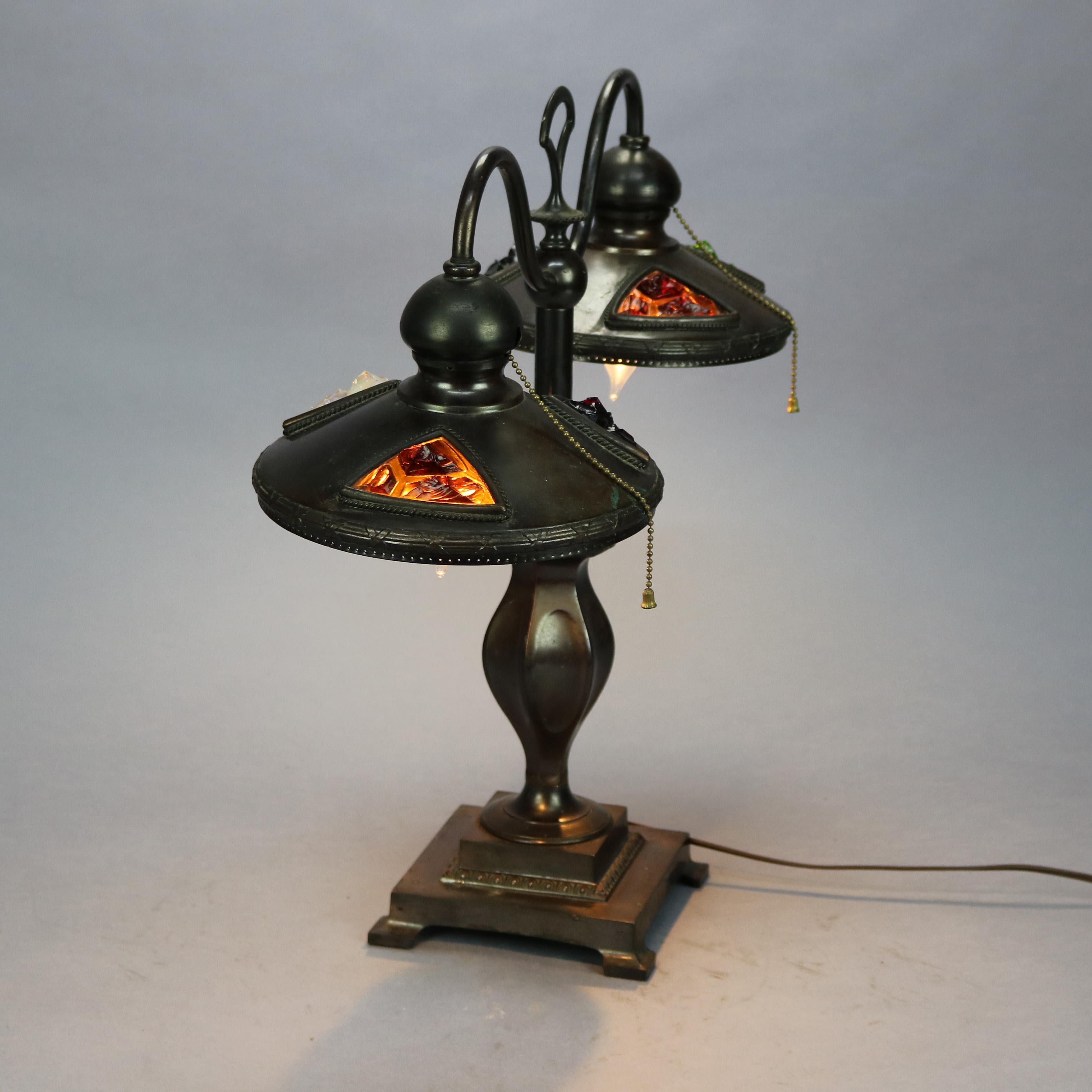 An Art Nouveau Austrian table lamp offers bronzed cast metal urn form base with double s-scroll arms terminating in light shades having chunk jeweled glass insets, wired for US electricity, c1910.

Measures: 19.5