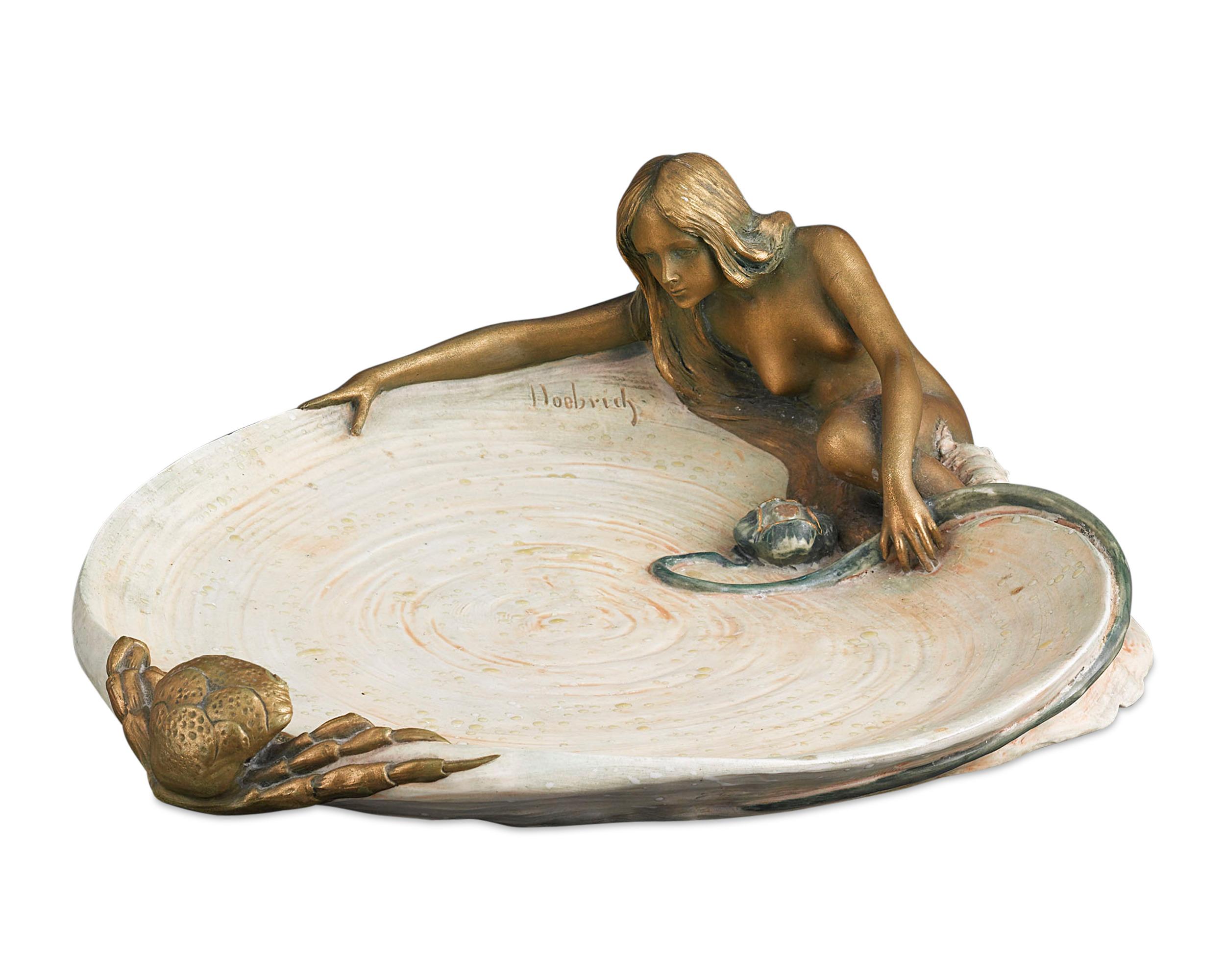 This enchanting Austrian pottery vide poche, or valet tray, is a fine example of the Art Nouveau style. The gently gilded and hand painted dish is intricately modeled as a nymph lying beside a lily pad watching a crab, with spot-glazed 