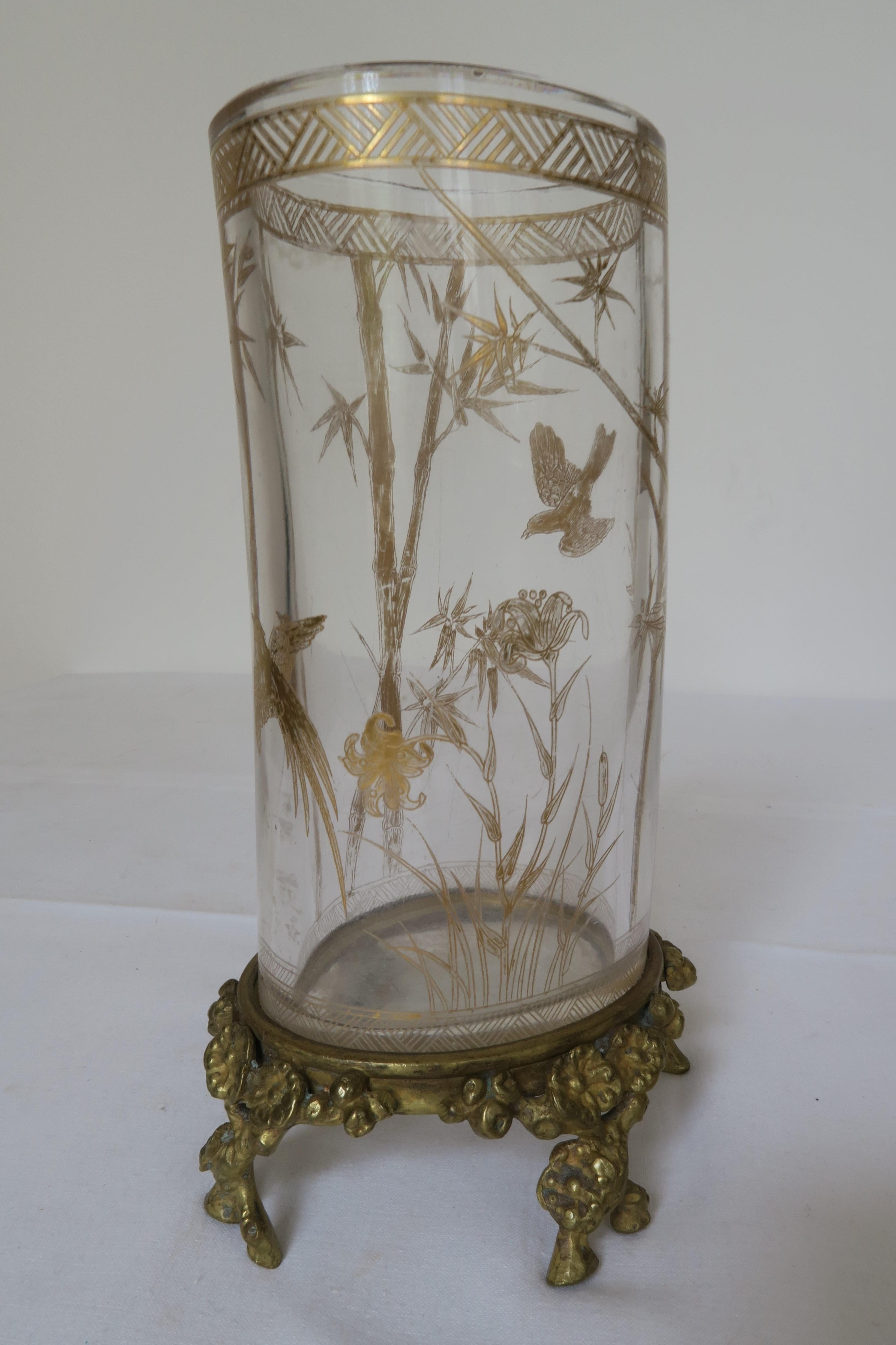 Nous vendons un vase spécial fabriqué par Baccarat. Le cylindre de verre légèrement courbé a été doré avec un motif complexe d'oiseaux, de fleurs et de bambous. Le pied du vase est également façonné en forme de brindilles ornées de fleurs
