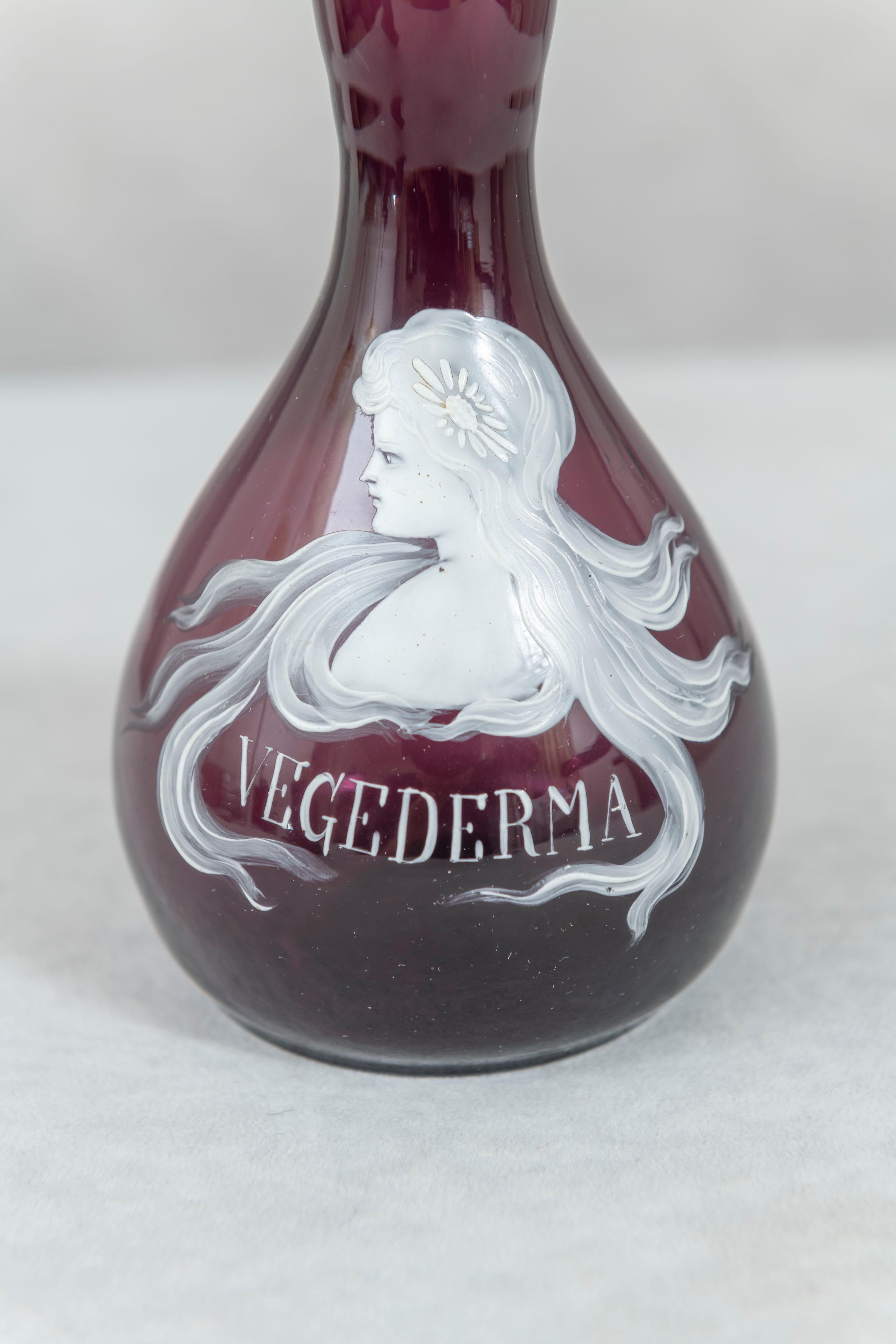 This period Art Nouveau bottle was used to hold Vegederma, a skin product. The beautiful young girl on the front is done by Mary Gregory. If you look up her work you will see glass with enameled relief patterns in white. Usually it's children,
