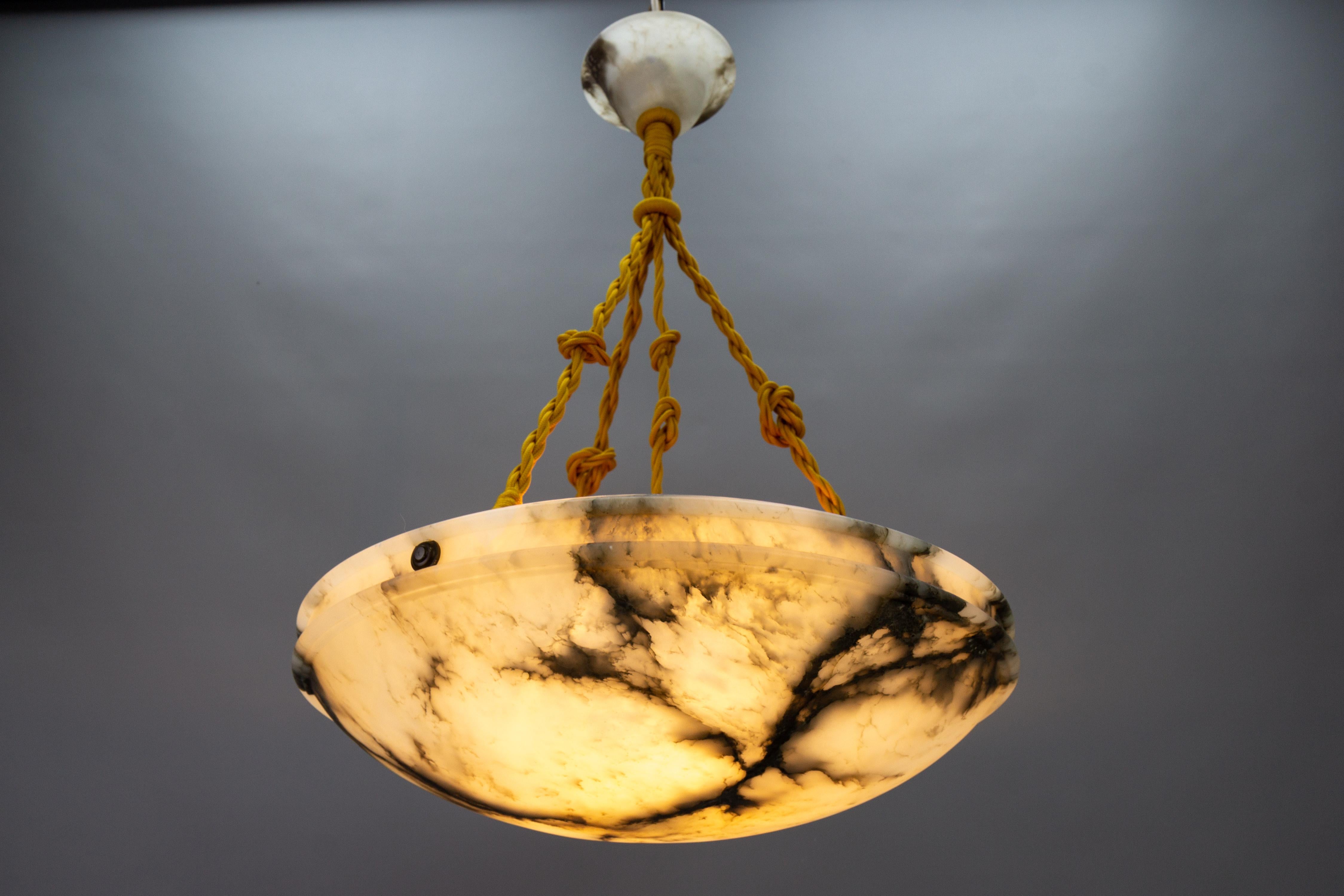 An elegant, round Art Nouveau period ceiling pendant light featuring a lampshade - a bowl - of white alabaster with impressive black and dark brown veins. Germany, around 1920.
In a masterfully carved form, this beautifully veined alabaster bowl is