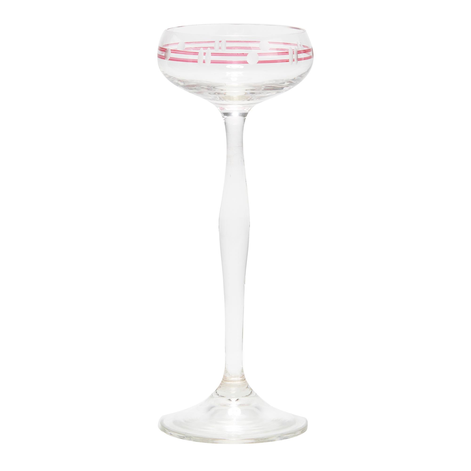 A stylish set eight Art Nouveau liqueur glasses with open rounded bowls with acid etched and engraved designs set within two cranberry enameled bands. The bowls are mounted on a tall shaped stem with a wide rounded foot of varying diameter. The