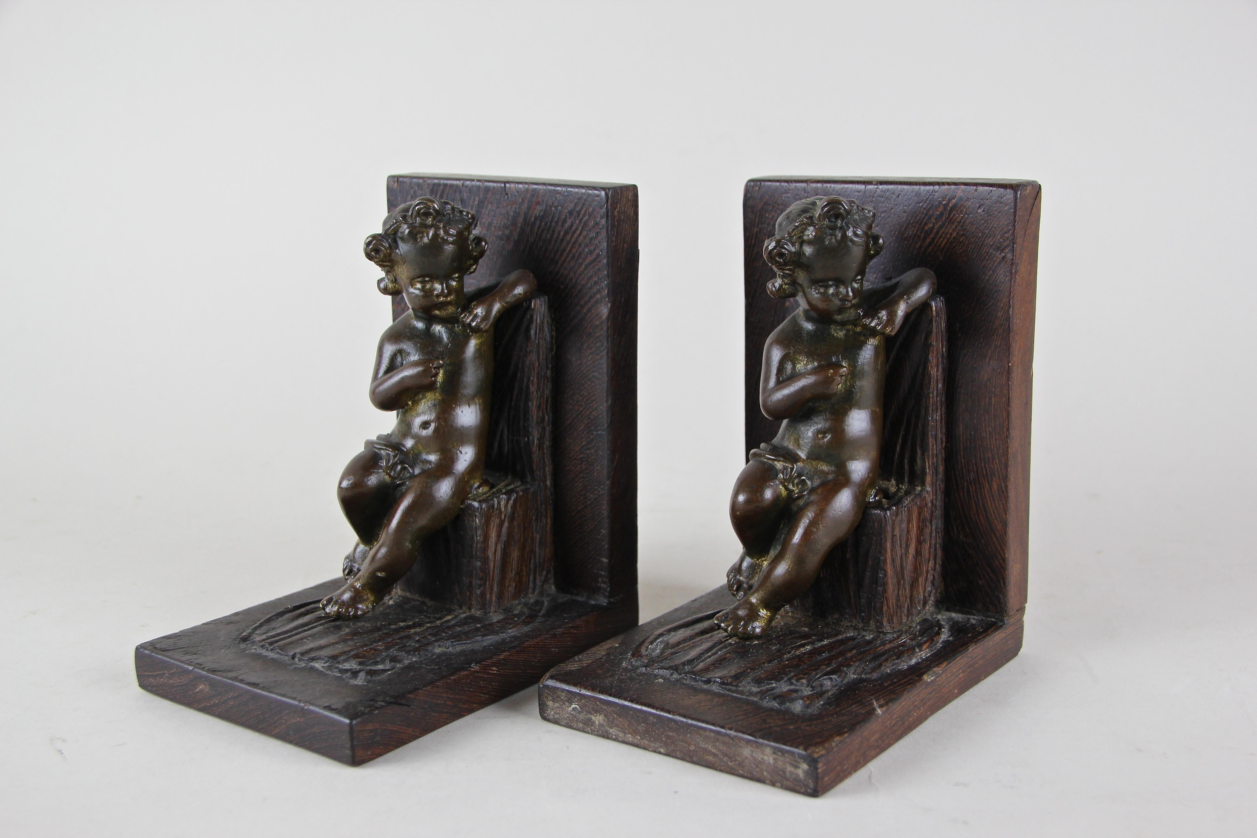 Lovely set of wooden Art Nouveau bookends adorned by putti sitting on a stool. The artfully designed Putti were made of solid bronze, all other parts were hand carved out of wood. An unusual set of over 120 year old bookends which will add an