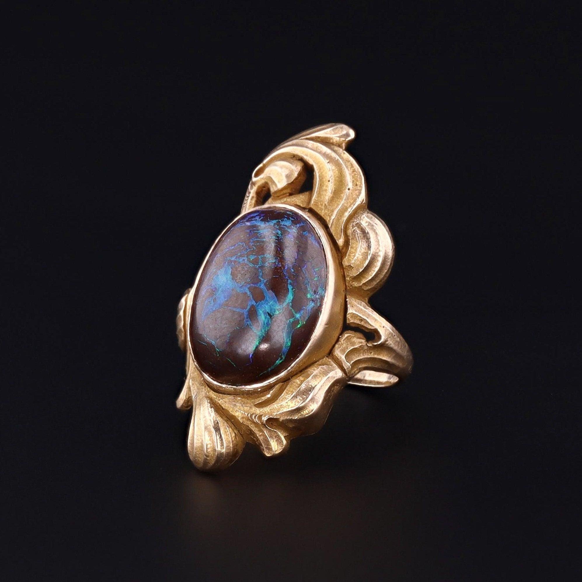 Ein fesselnder Boulder-Opal-Ring mit einer schokoladenbraunen Matrix, die mit leuchtend blauen Adern akzentuiert ist.

Die elegante asymmetrische Fassung ist aus 10 Karat Gold und stammt aus der Zeit des Jugendstils (um 1910). Der Boulder-Opal ist