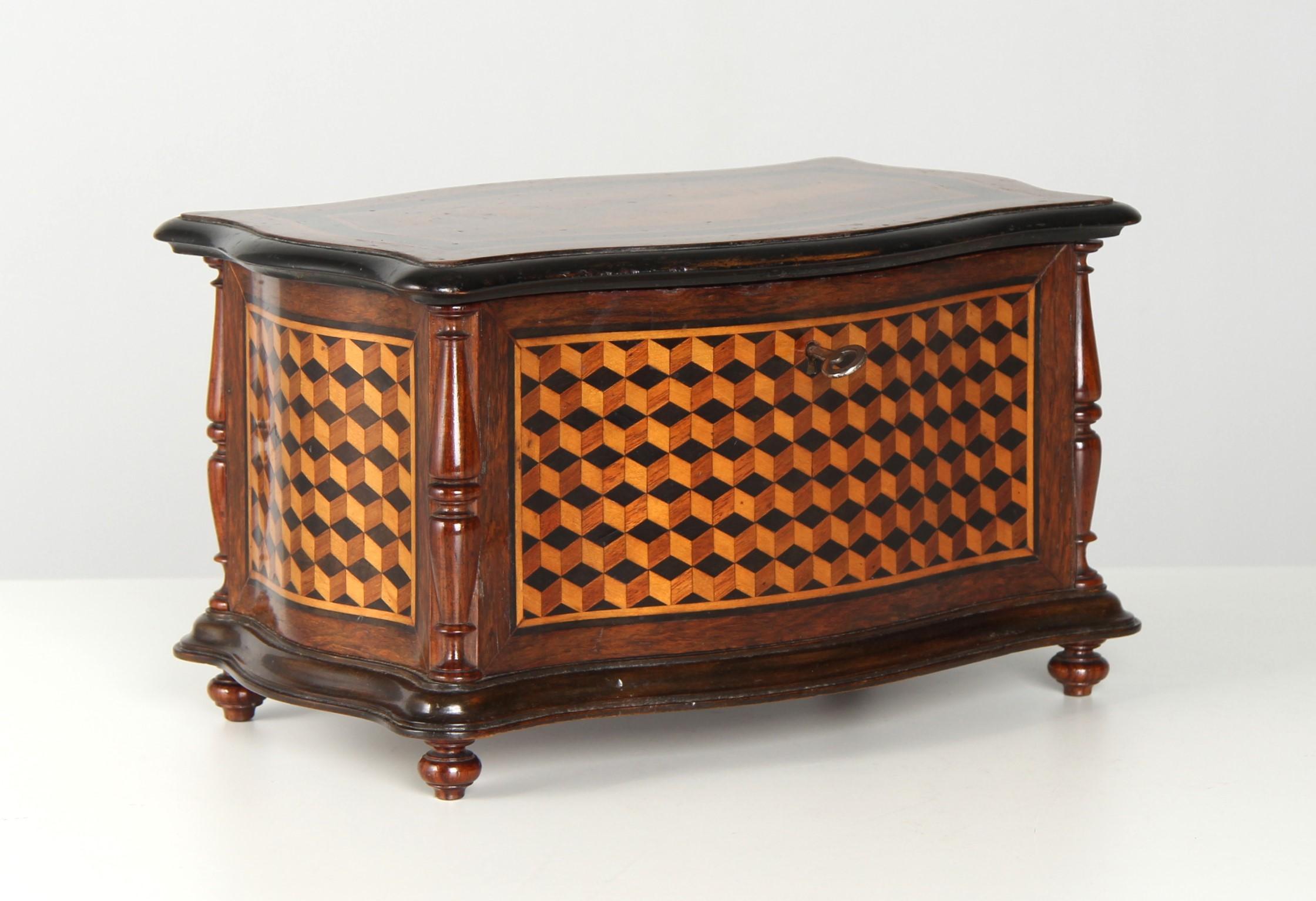 Antigua caja o joyero Art Nouveau con hermosa marquetería.

La caja curvada está decorada en todo su contorno con la llamada marquetería cúbica. Disponiendo hábilmente maderas de distintos colores, el creador ha conseguido crear un efecto