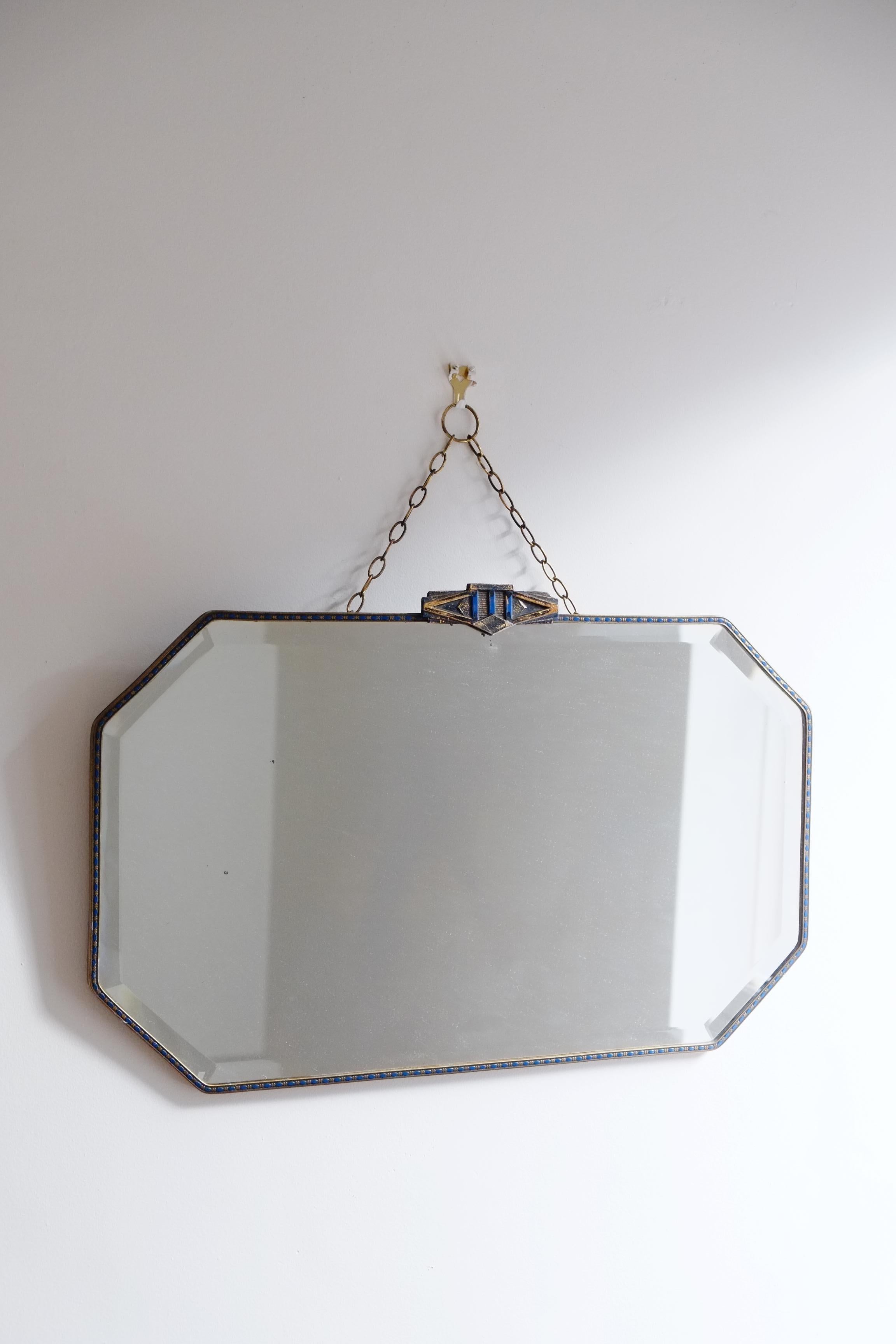 Bellissimo specchio da parete antico proveniente dall'Inghilterra. Questo specchio ha una bellissima cornice in ottone con un dettaglio smaltato blu intorno all'intero pezzo. La parte superiore dello specchio presenta un dettaglio geometrico con