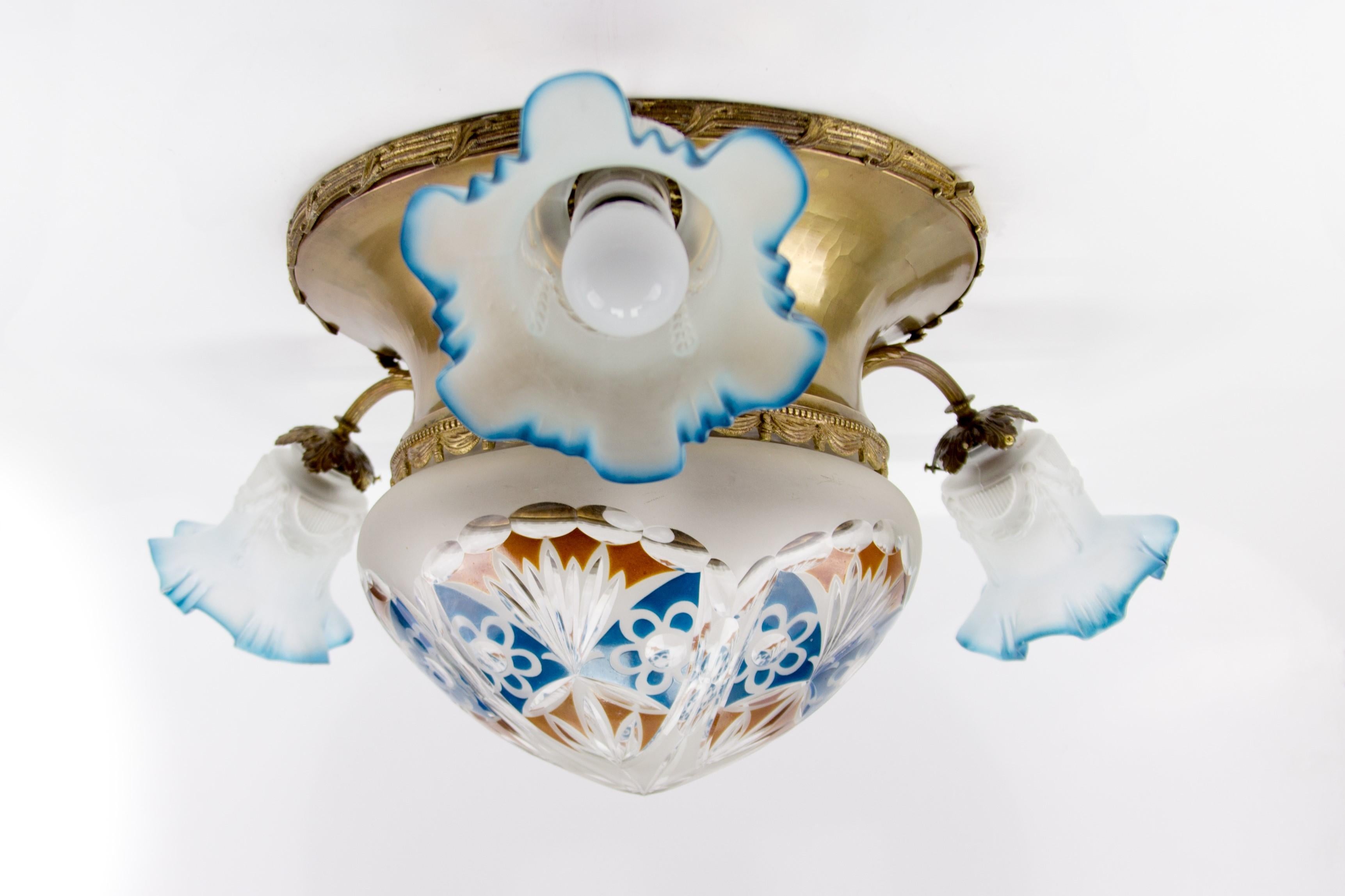 A wonderful Art Nouveau style brass and glass flush mount four-light fixture/ceiling lamp from the 1930s. With frosted white, blue, and red cut-glass central bowl/glass shade and three frosted glass lampshades with a blue edge. The ceiling lamp has