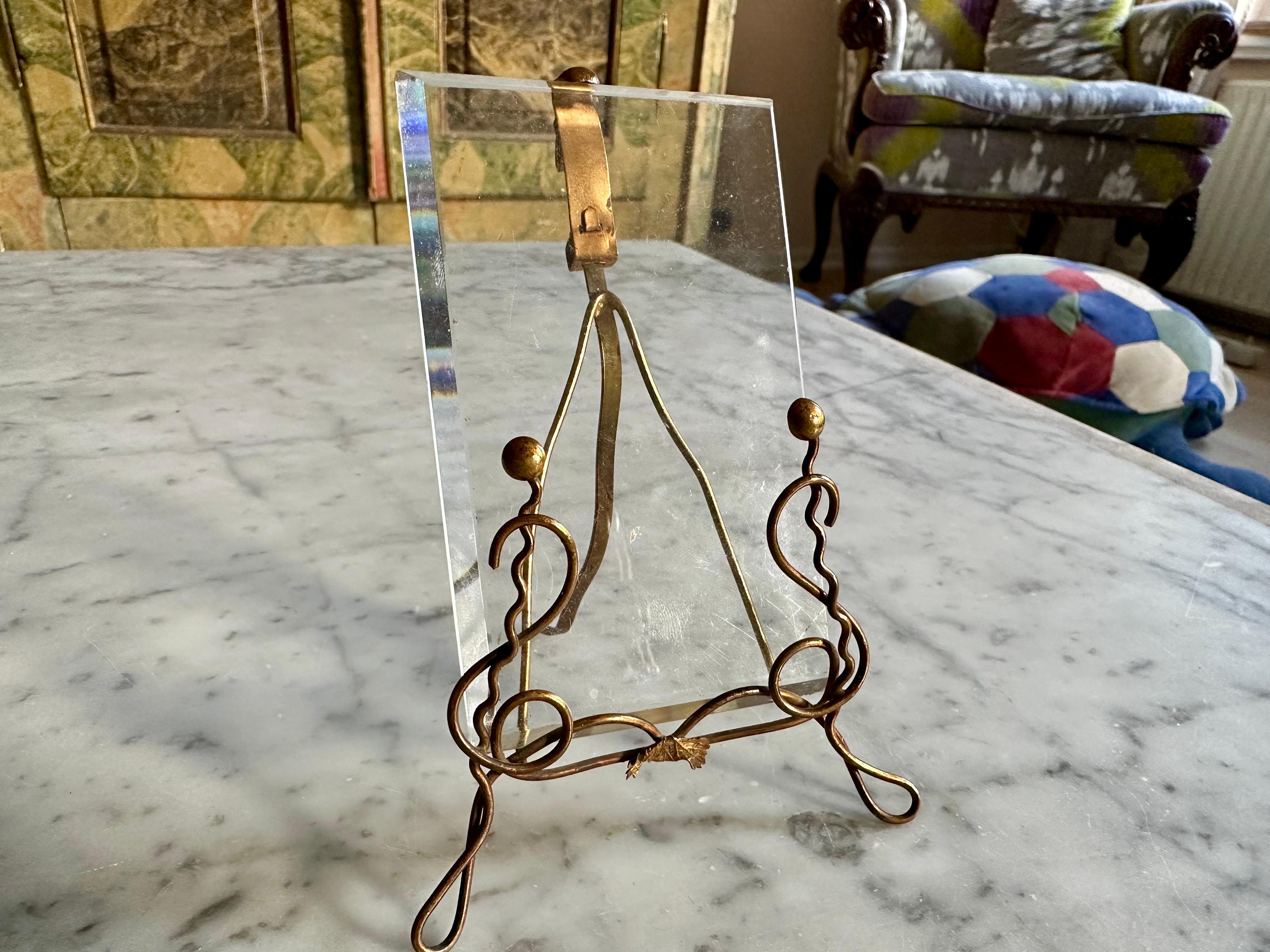 This exquisite Art Nouveau picture frame, likely crafted in Vienna around 1900, embodies both elegance and simplicity. Made from bent brass, it features a beautifully curved design that gracefully holds a thick-cut glass plate. The photo is inserted