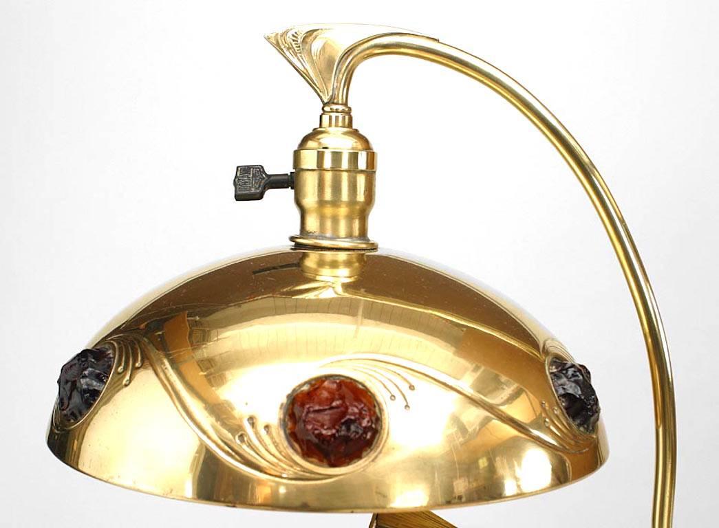 Lampe de table Art Nouveau en laiton avec tête à la base et inserts en pierre sur l'abat-jour.
