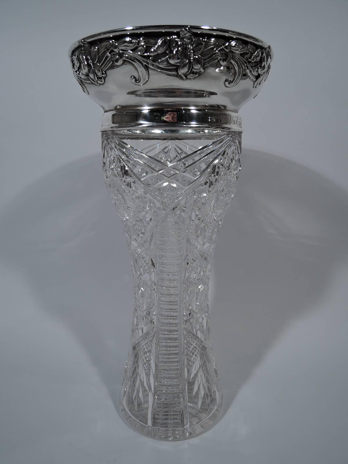 Art Nouveau brilliant-cut glass and sterling silver vase. Made by Gorham in Providence in 1909. Clear glass waisted cylinder with cut ornament. Sterling silver collar and curved and wide mouth with applied floral garland. Engraved interlaced script