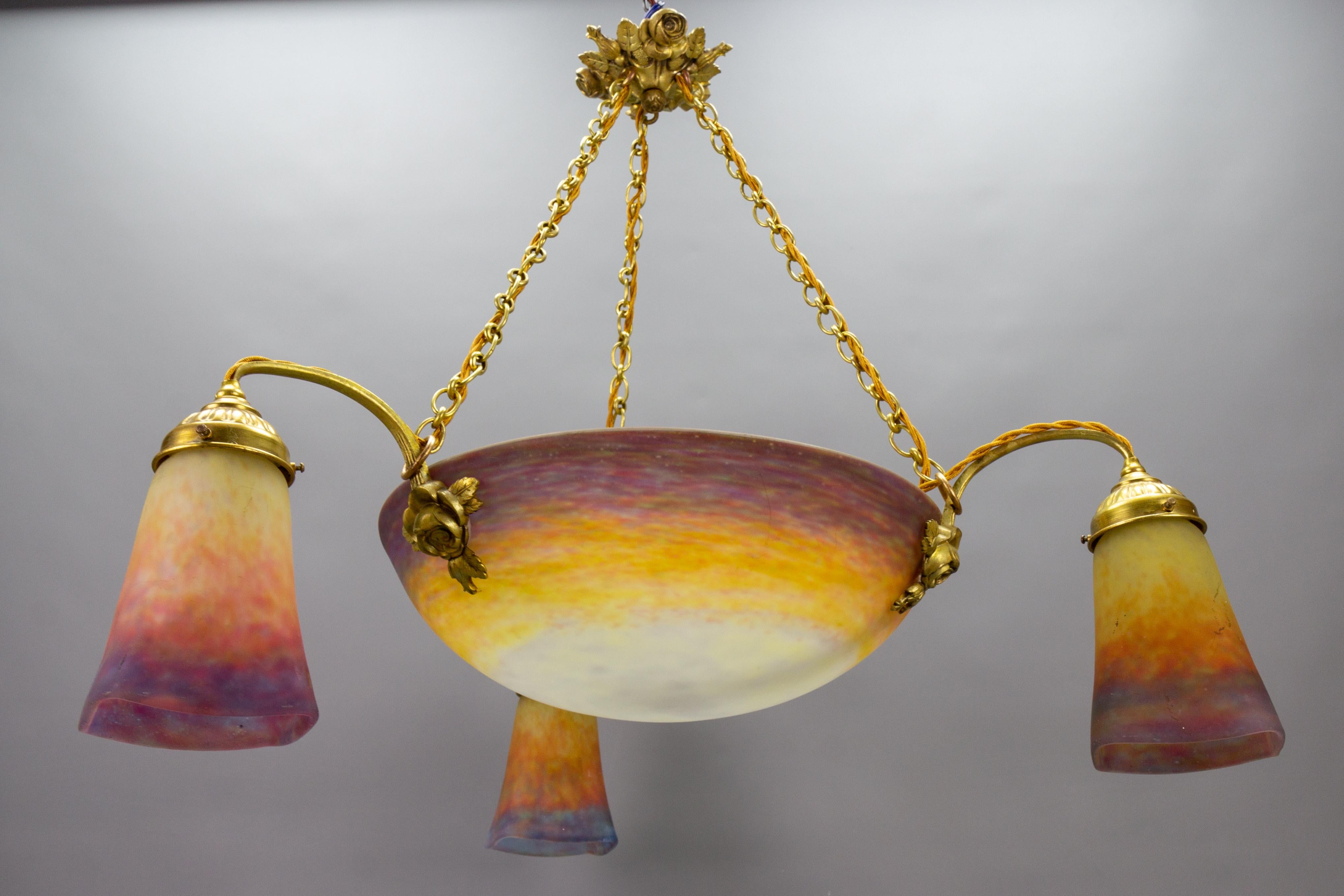 French Art Nouveau bronze and Muller Frères Lunéville polychrome glass four-light chandelier, circa 1920.
This impressive French Art Nouveau period chandelier features a mottled “Pâte de Verre” central, beautifully colored glass bowl and three glass