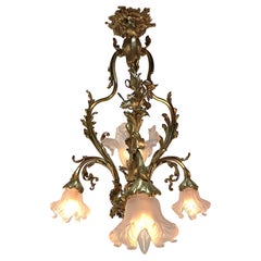 Lampadario Art Nouveau in bronzo con paralumi in vetro soffiato.