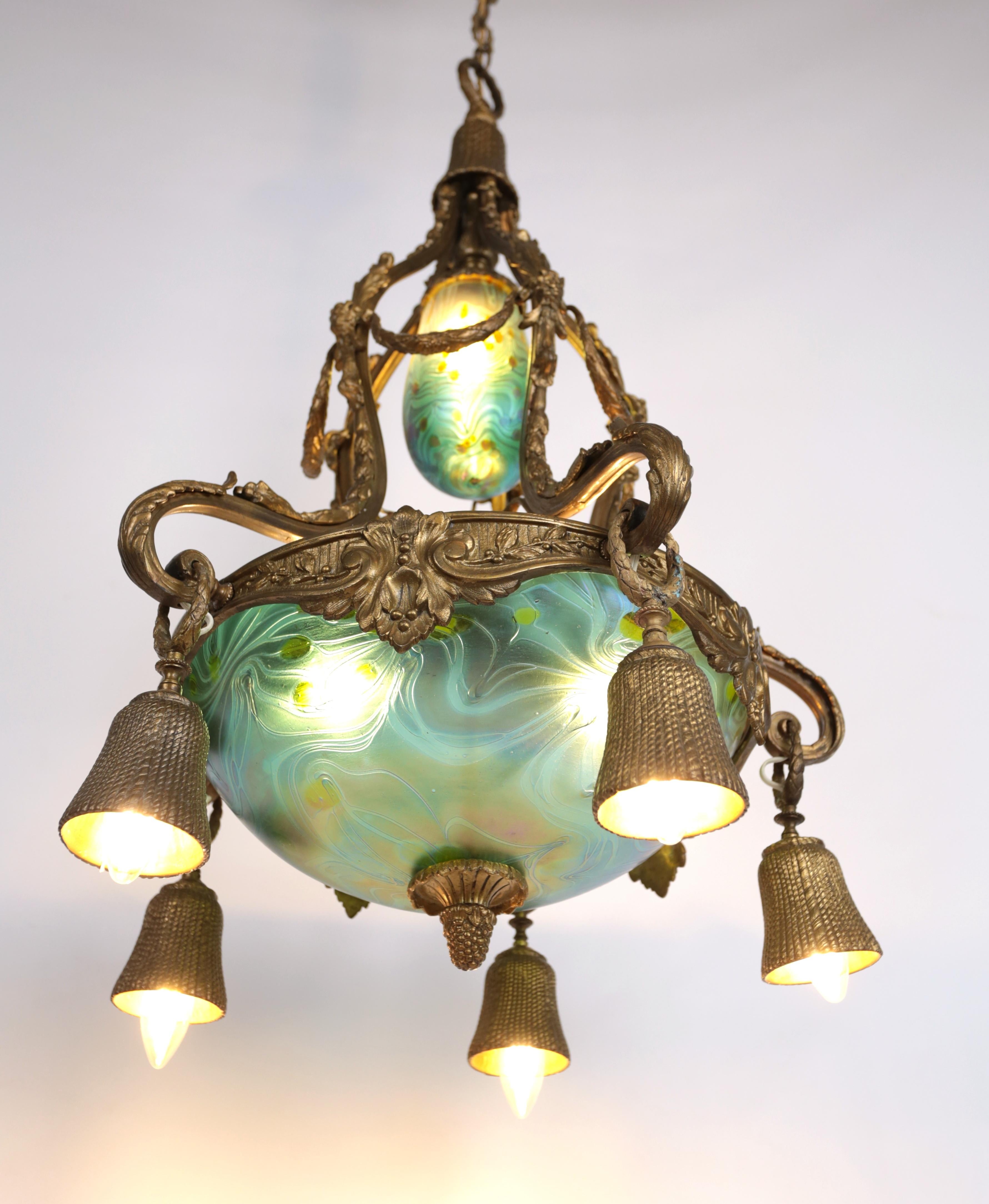 Art Nouveau bronze chandelier with iridescent glass shades
A luxurious model of a chandelier from the Art Nouveau period. The body of the chandelier is made of patinated bronze with rich plant decoration and perfectly rendered details. The